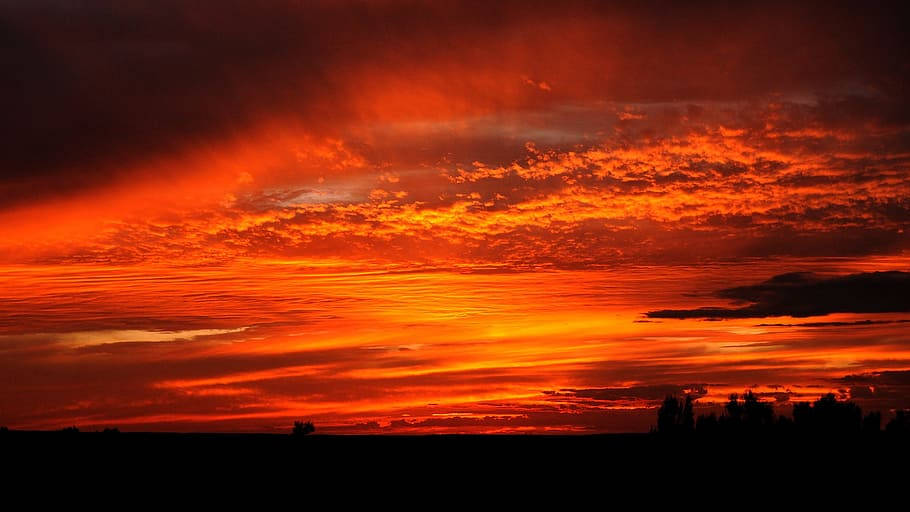 蒙古地區的夕陽 壁紙 — 熾熱的橙色和紅色日落，在黑暗的剪影地平線上方，用戲劇性的雲彩描繪天空。