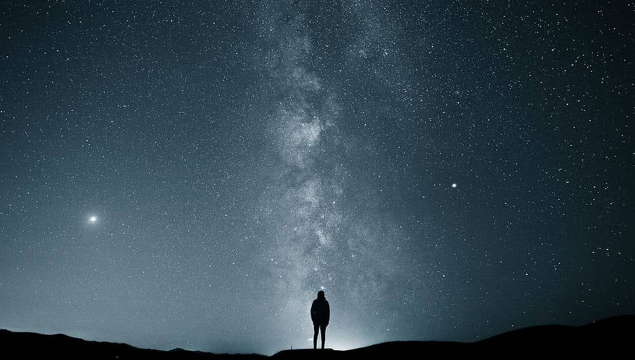 蒙古夜空下的剪影 壁紙 — 一個孤獨的身影站在山頂上，仰望在繁星點點的夜空中閃耀的銀河系。