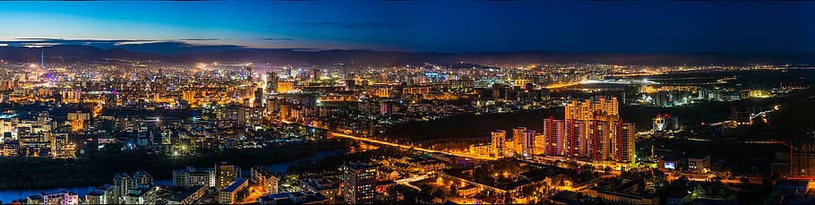 蒙古烏蘭巴托全景夜景 壁紙 — 深藍色天空下，一座廣闊城市在夜晚的全景視圖，建築物和街道散發著閃爍的燈光。