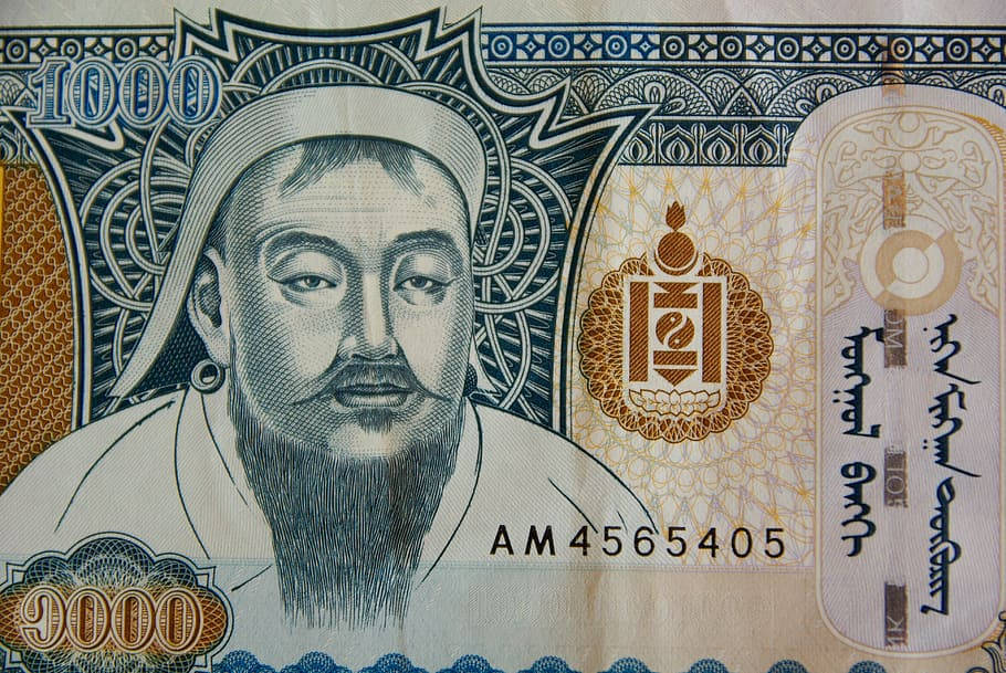 蒙古紙幣上的成吉思汗 壁紙 — 蒙古1000圖格里克紙幣特寫，特徵為一位留鬍鬚的男子穿著傳統服飾，帶有複雜的藍色、金色和白色圖案。
