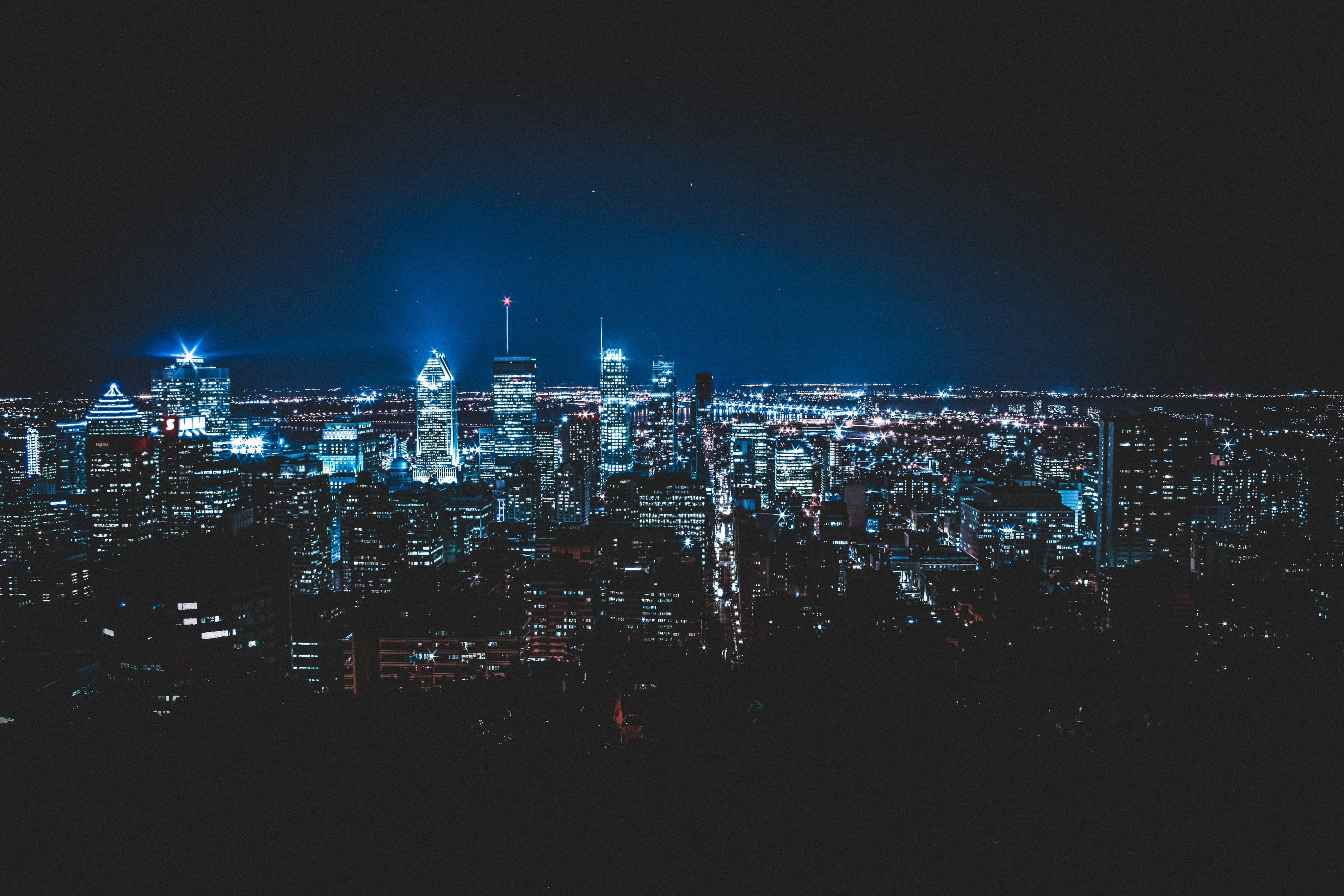 蒙特利爾夜間城市天際線 壁紙 — 廣闊的城市天際線在夜晚沐浴在冷藍色霓虹燈光下，映襯著黑暗的天空。