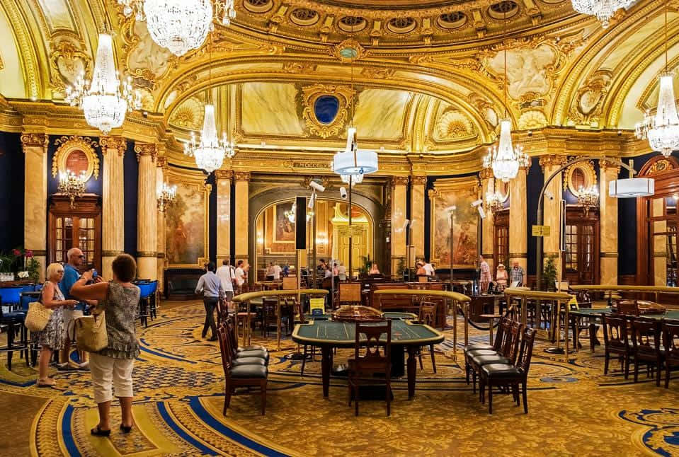 宏偉的賭場大廳，金色裝飾和正在玩遊戲的顧客。