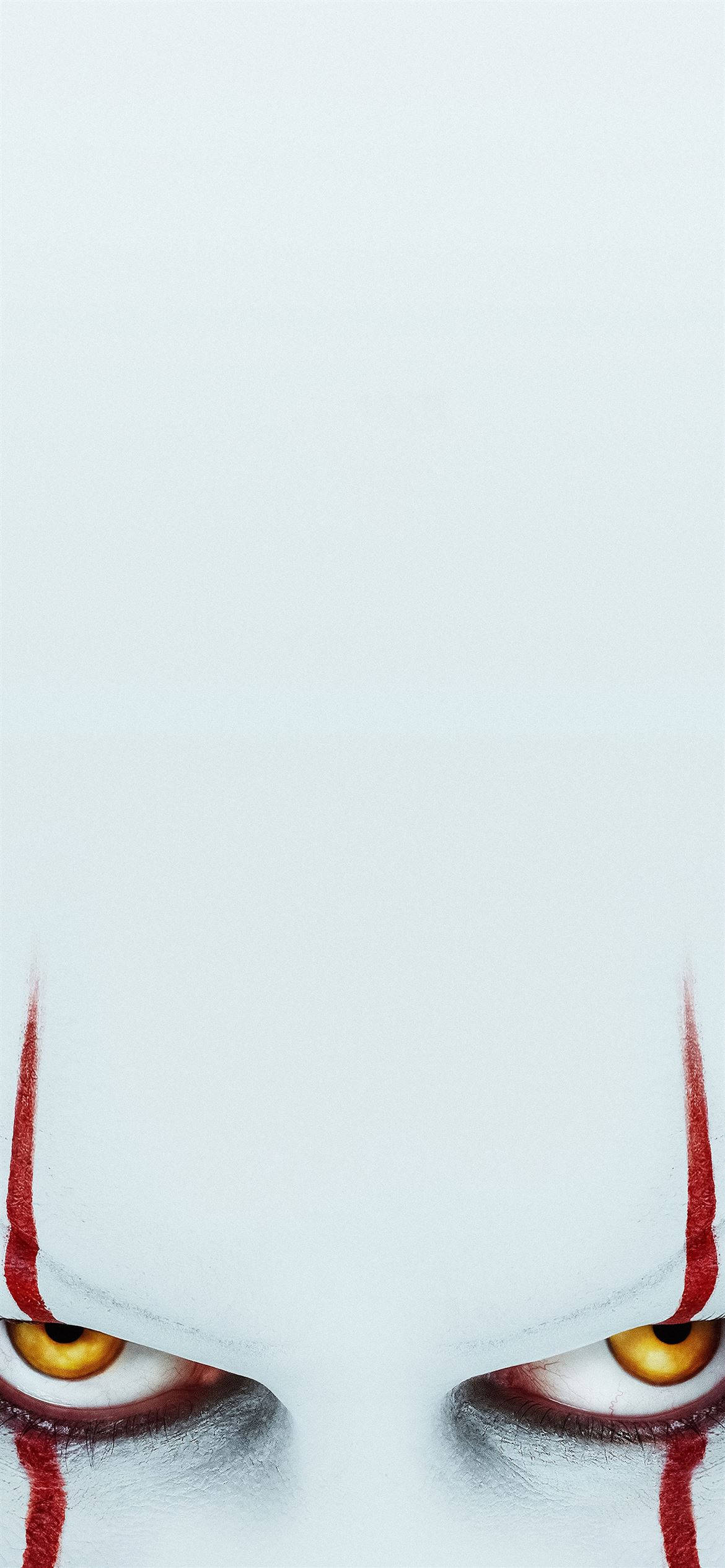 Pennywise iPhone 12 壁紙 — 蒼白臉部特寫，帶有強烈的黃色眼睛和從眼角流下的紅色條紋。