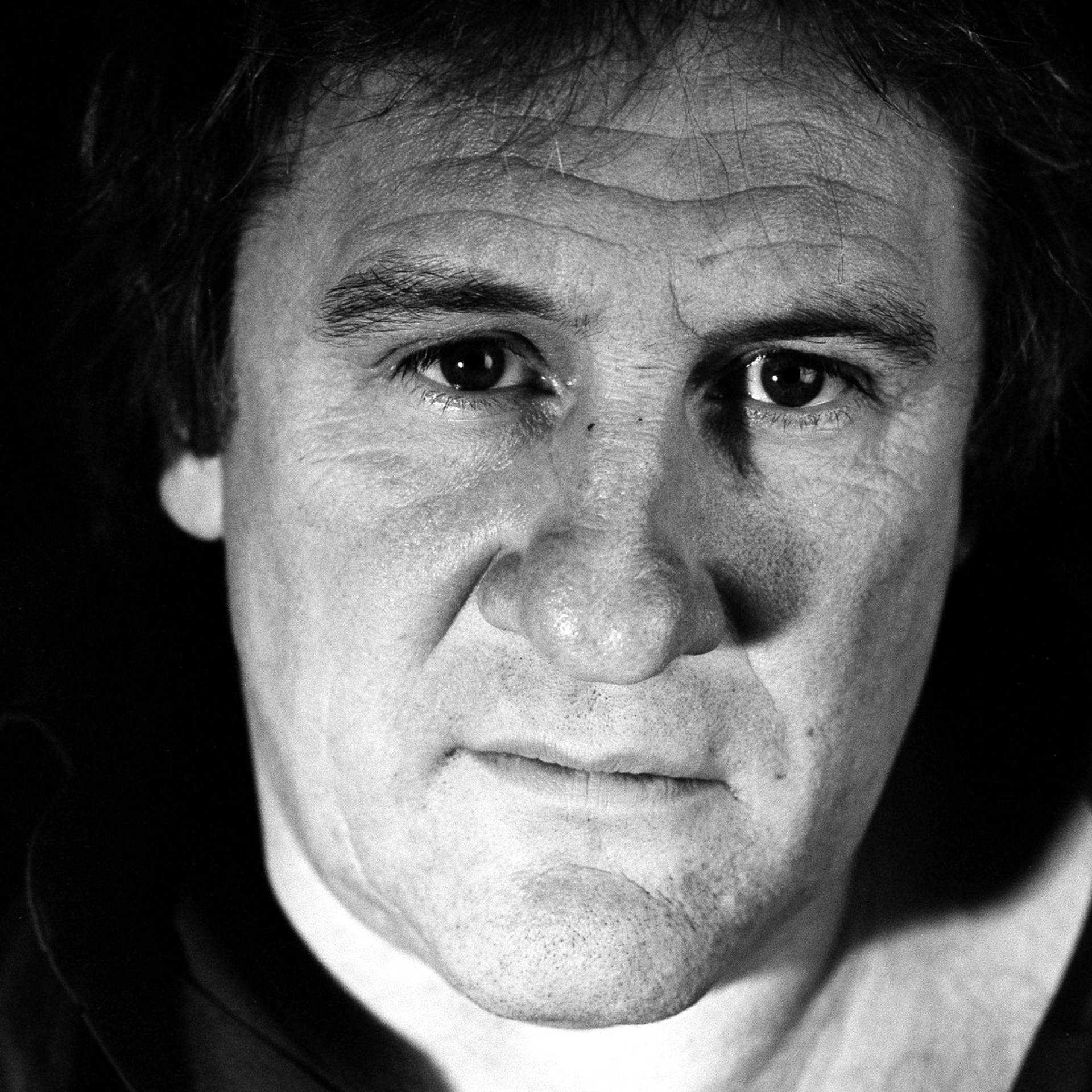 眼神銳利的嚴肅男性黑白特寫肖像。