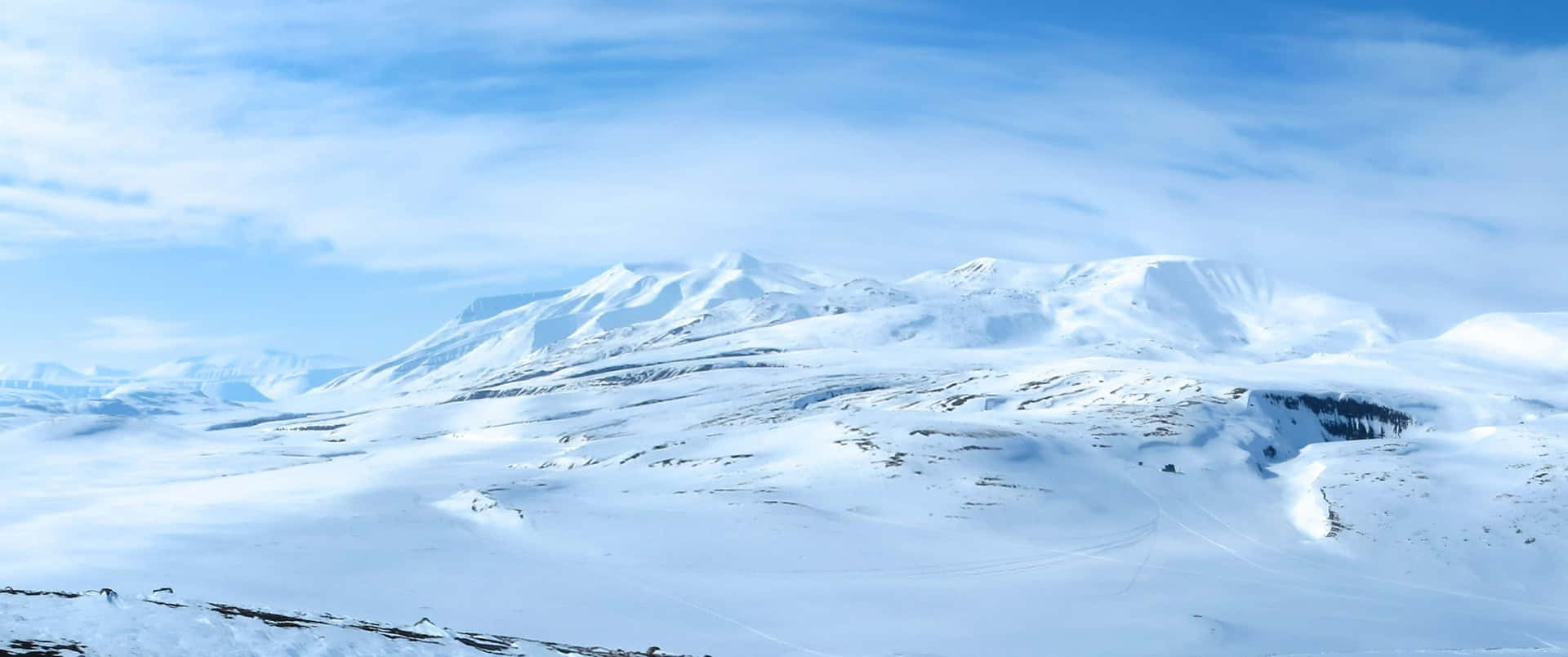 晴朗藍天和零星雲朵下的雪山。