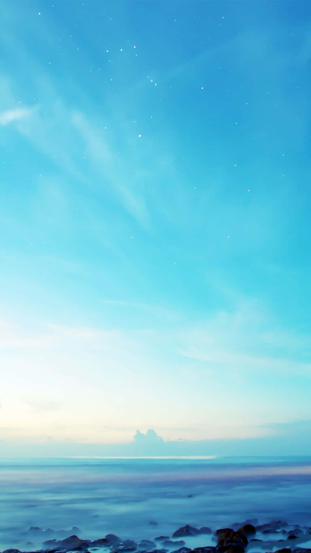 暮色中平靜的海洋，在岩石海岸上方的藍色天空中可見星星。
