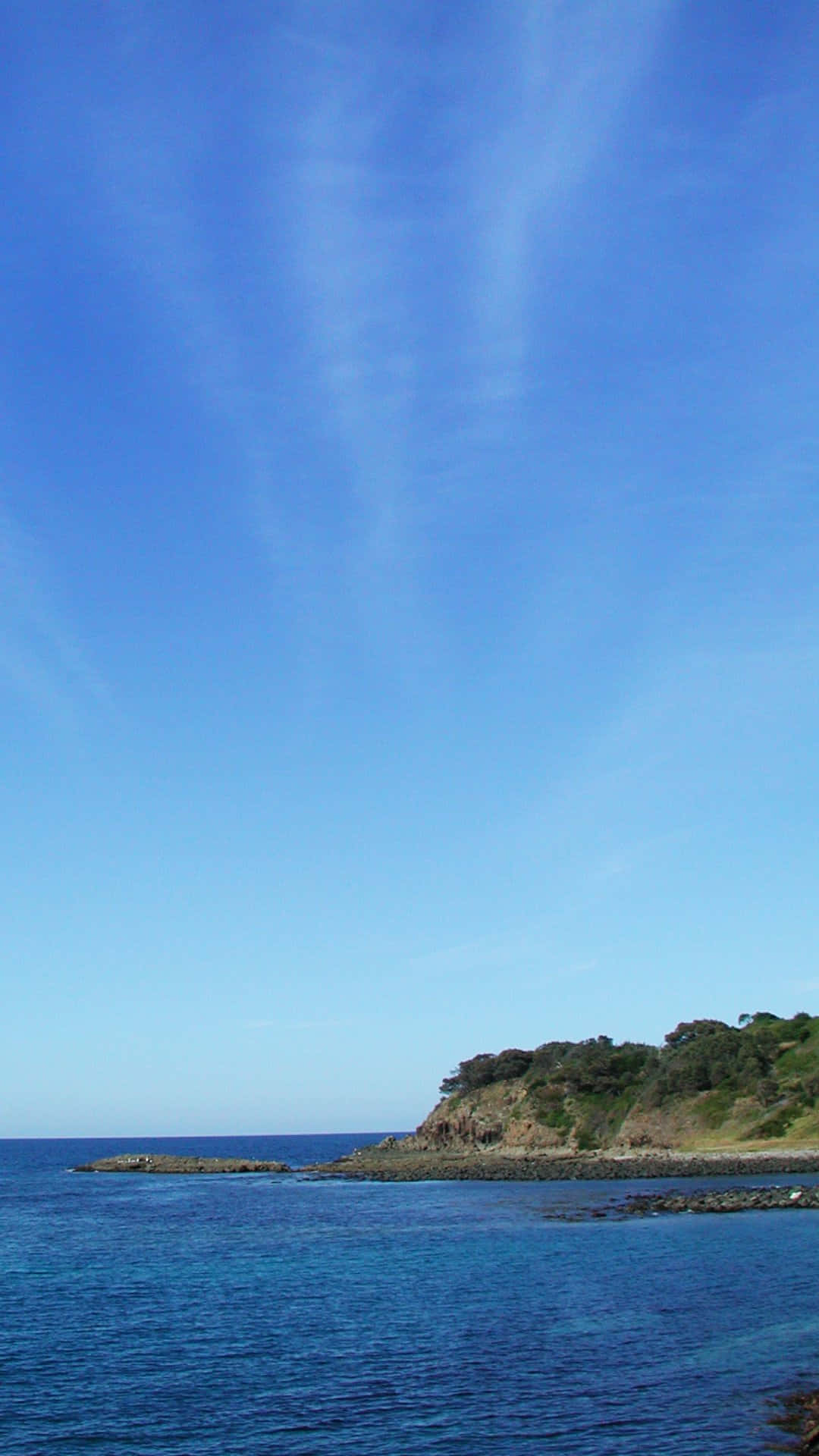 蔚藍海岸寧靜風景 壁紙 — 寧靜的海岸景色，深藍色的海洋與岩石海岸相接，廣闊晴朗的天空中飄著縷縷白雲。