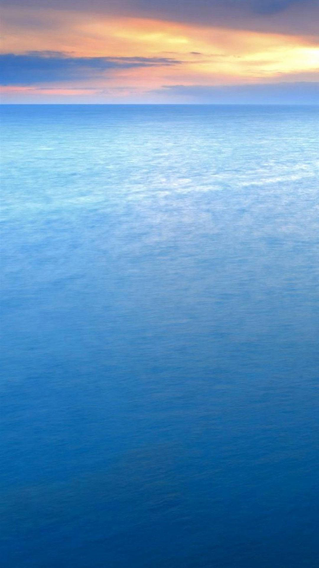 日落時平靜的海洋，地平線上有橙色和紫色的雲彩。 — 主螢幕 壁紙