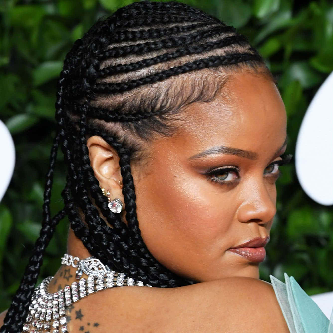 Rihanna 佩戴華麗鑽石首飾，辮子頭髮和星星紋身。