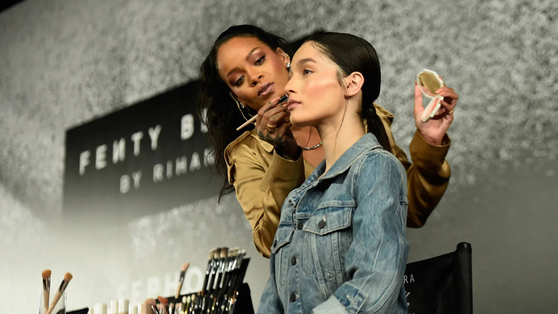 Rihanna 在 Fenty Beauty 活動中為模特兒化妝。
