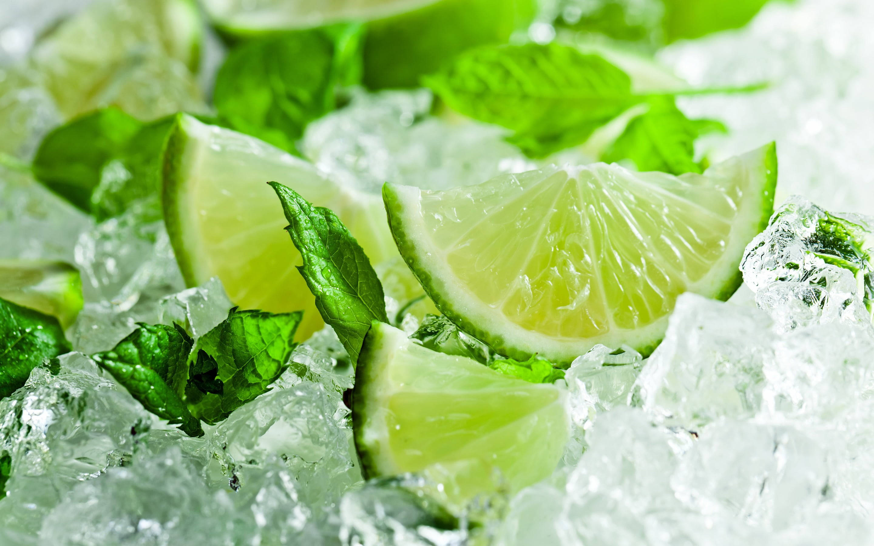 薄荷綠檸檬配薄荷葉 壁紙 — 新鮮青檸角同薄荷葉放喺閃閃發光嘅冰塊上，形成充滿活力嘅綠色同白色構圖。
