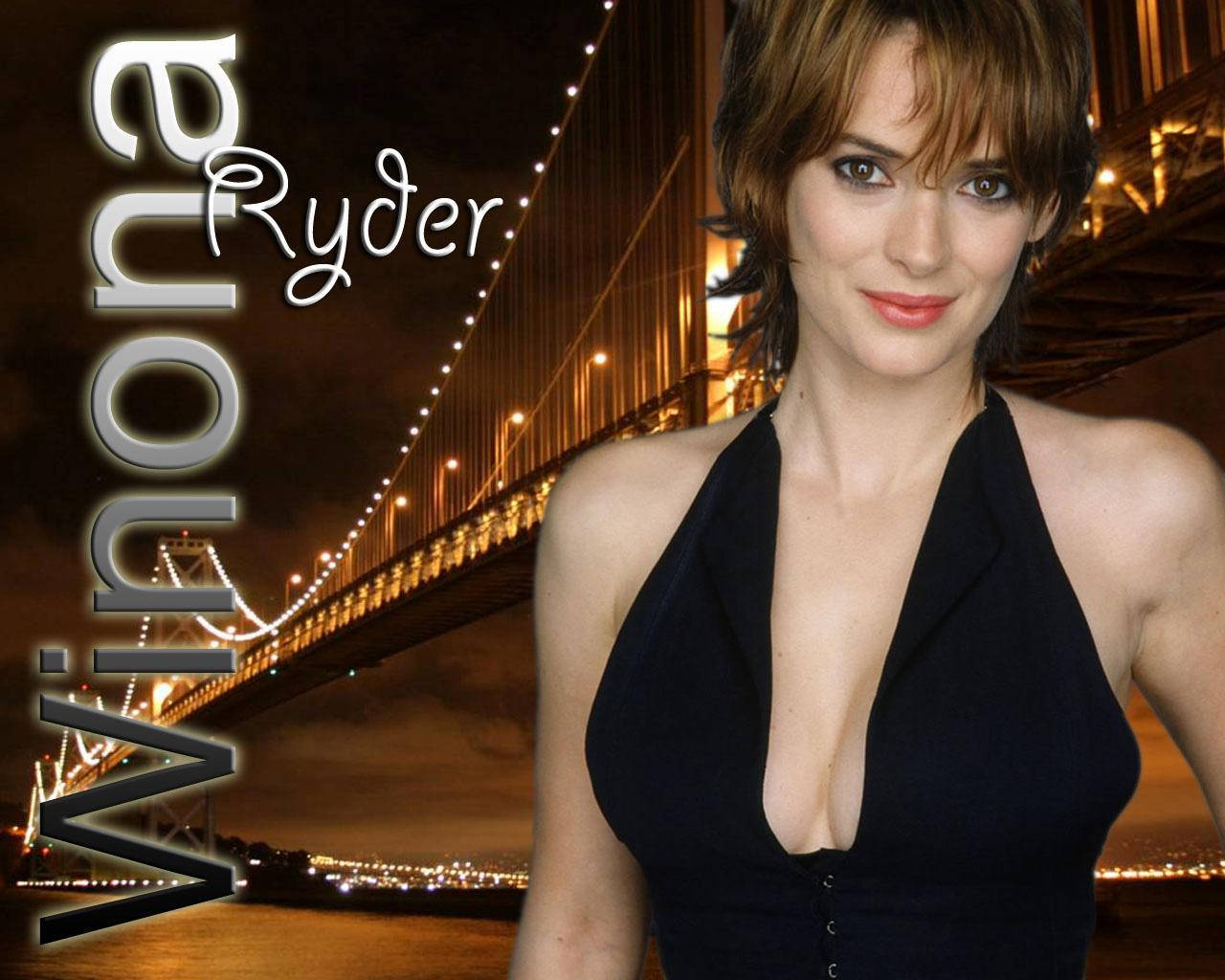 薇諾娜·瑞德與曼哈頓大橋 壁紙 — Winona Ryder 穿著黑色連衣裙，在發光的夜間橋樑背景和城市燈光下微笑。