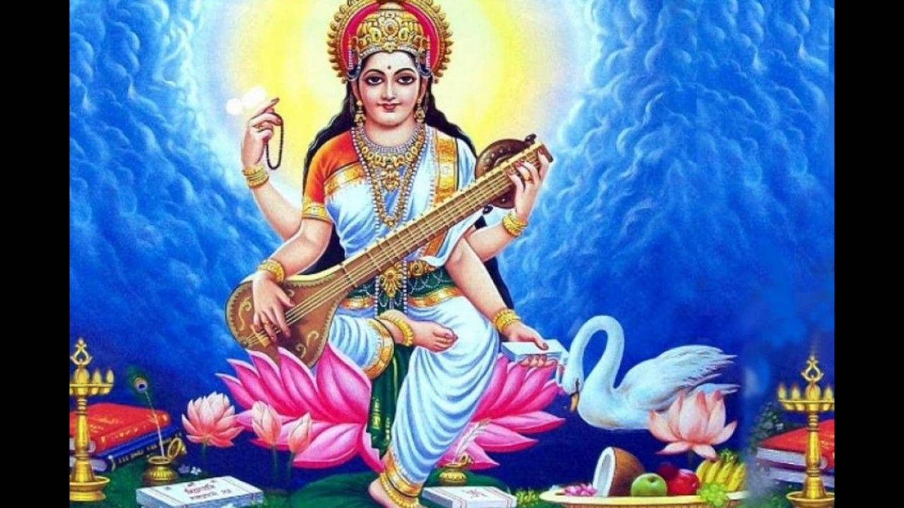 薩拉斯瓦蒂女神與日空背景 壁紙 — 神聖的女神薩拉斯瓦蒂優雅地坐在粉紅色的蓮花上，手持維納琴，身旁有一隻天鵝，背景是燦爛的藍色。