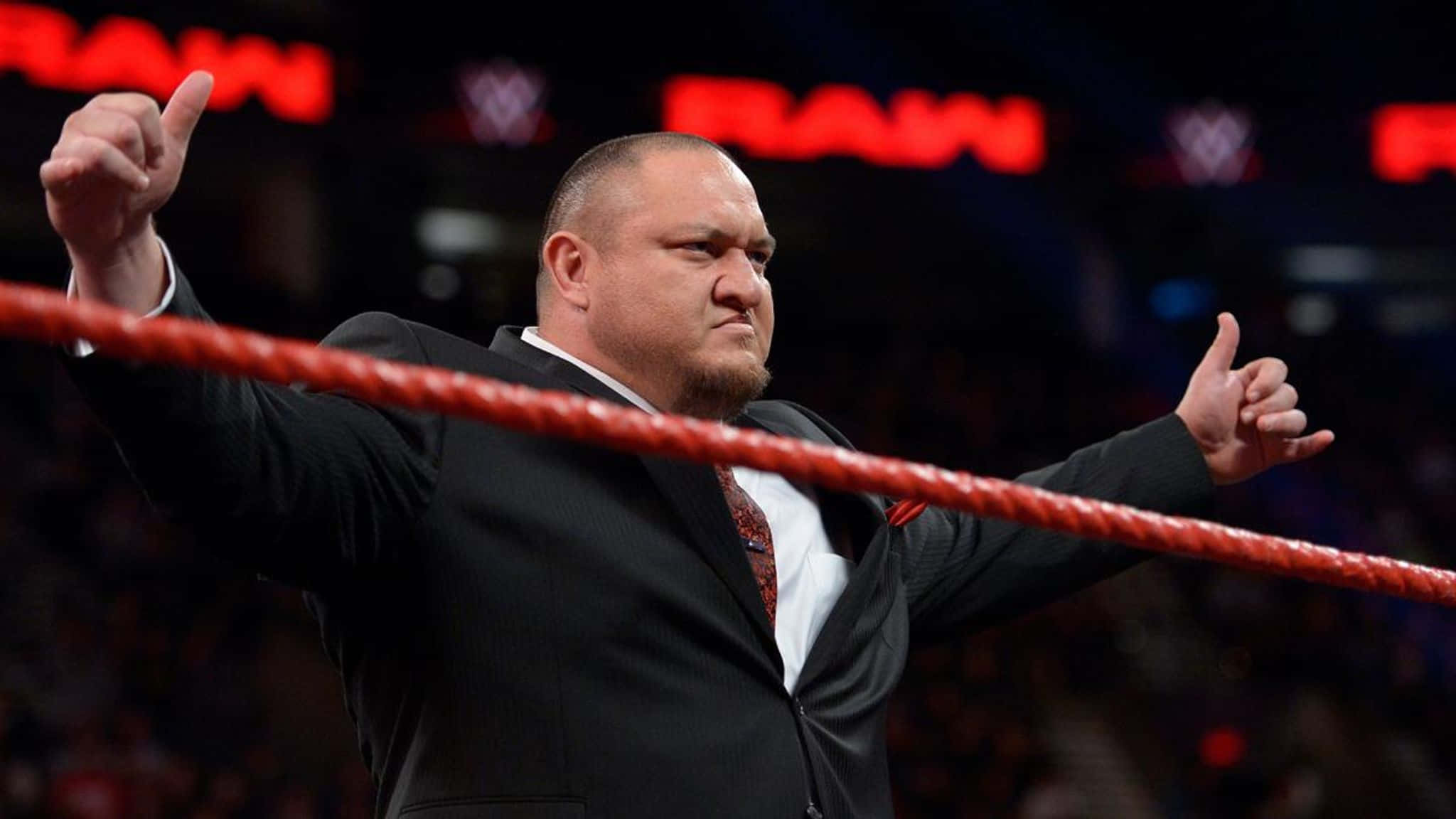 薩摩亞·喬於WWE Raw展現經典Limitless姿勢 壁紙 — 身穿黑色西裝的摔角手在紅色擂台內豎起兩個大拇指，身後有「RAW」燈光閃耀。