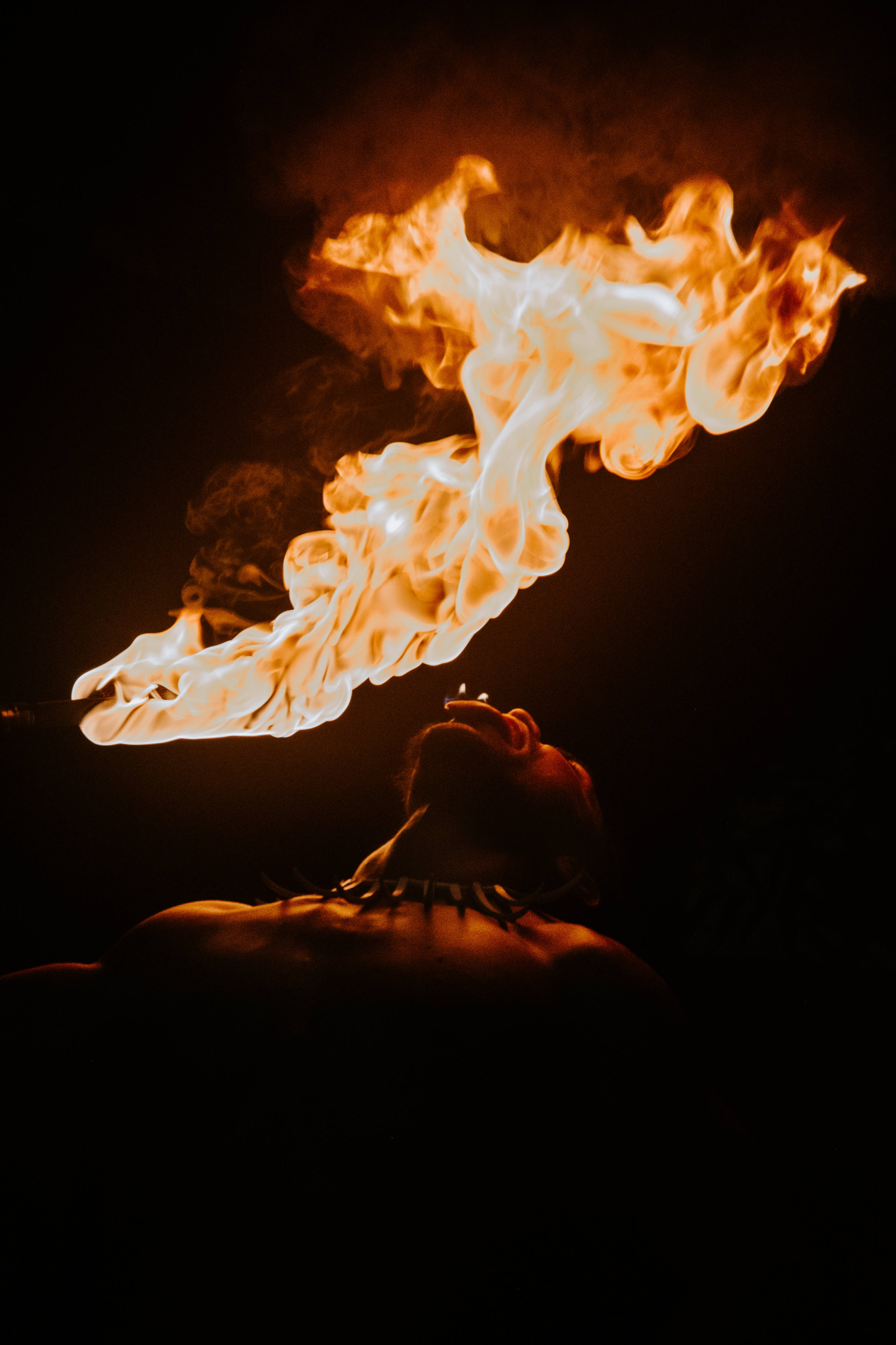 薩摩亞夜晚火舞者 壁紙 — 一個人在漆黑背景前呼出一股橙白色火焰的戲劇性爆發。