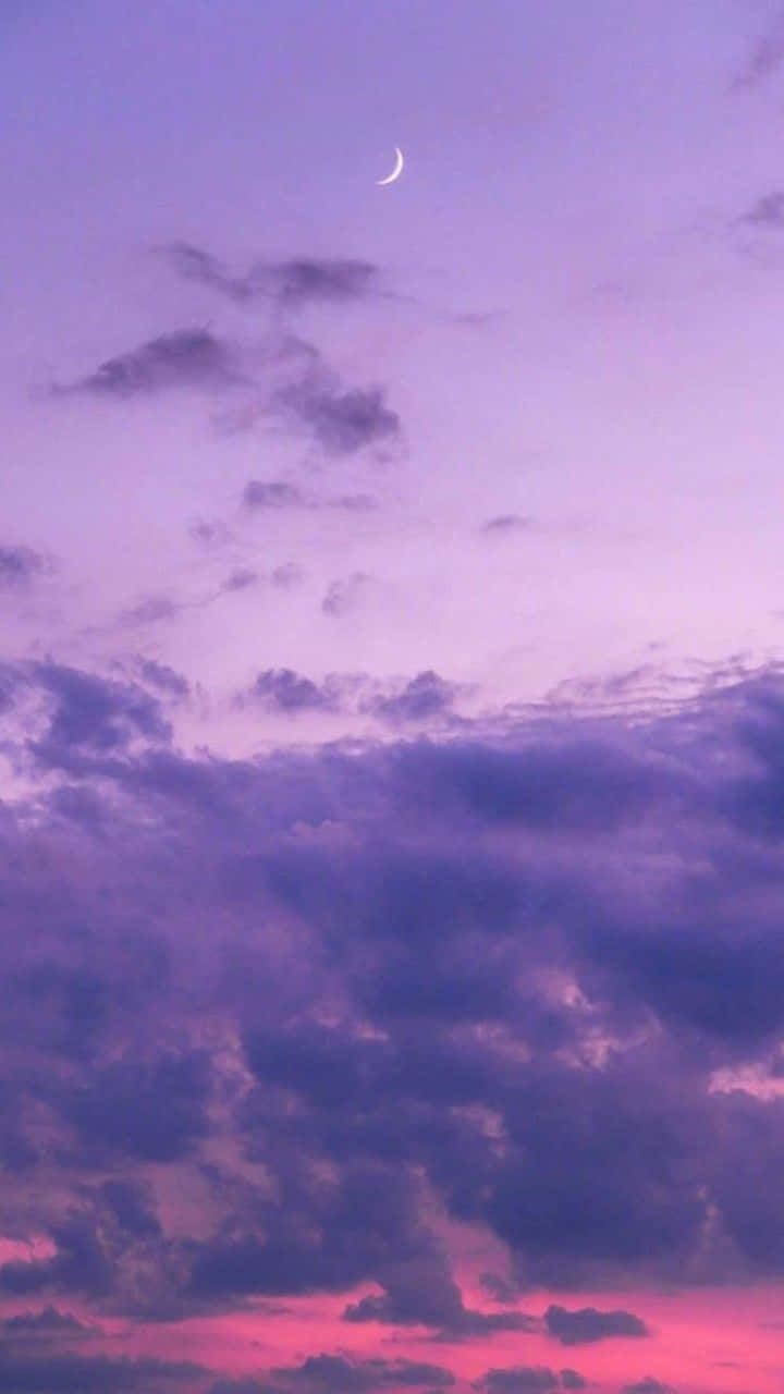 薰衣草紫色天空與烏雲 壁紙 — 一彎新月在暮色中柔和的紫色和粉紅色雲朵上方發光。