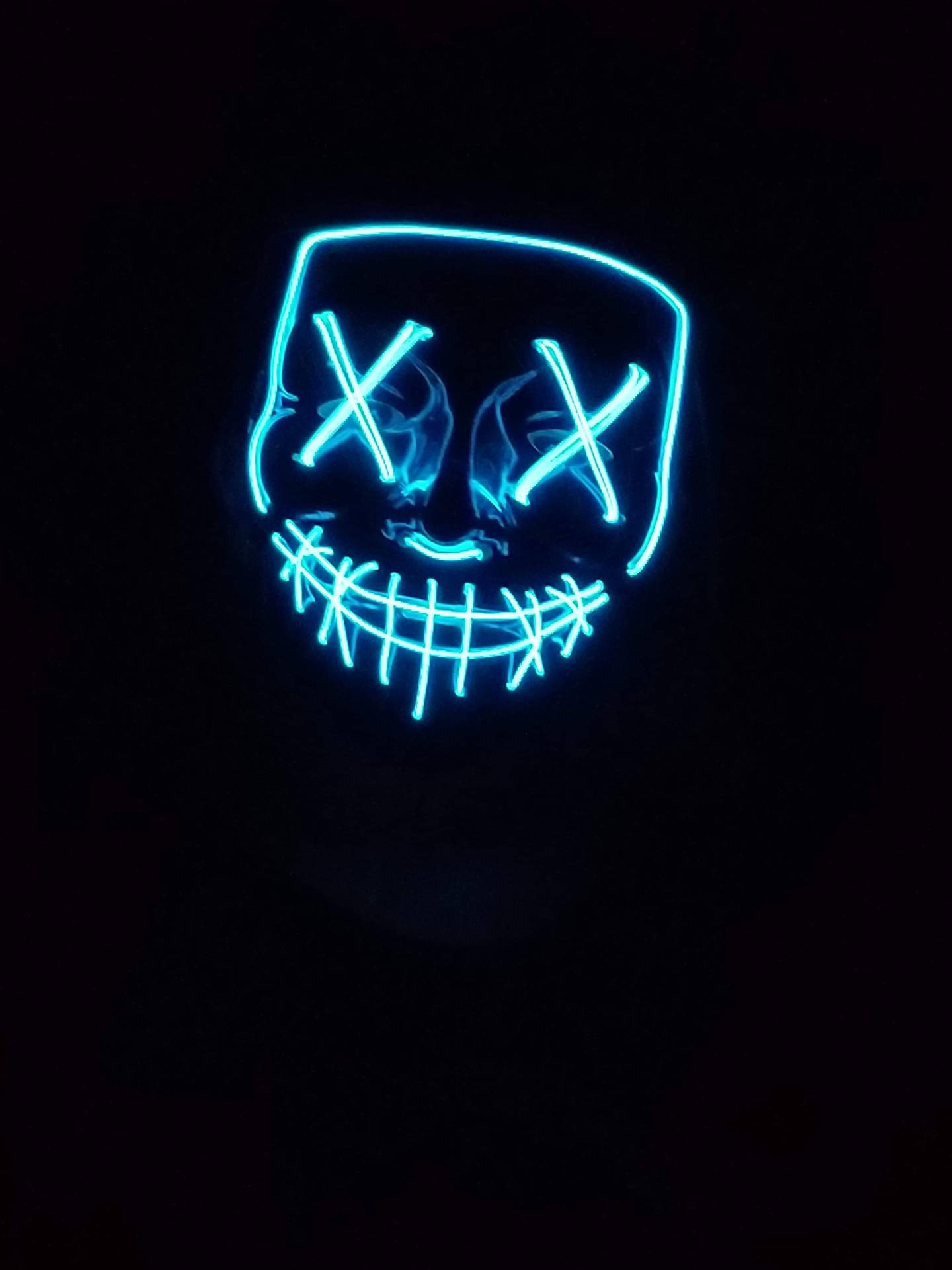黑暗中一個帶有X形眼睛和縫合嘴巴的藍色發光LED面具。