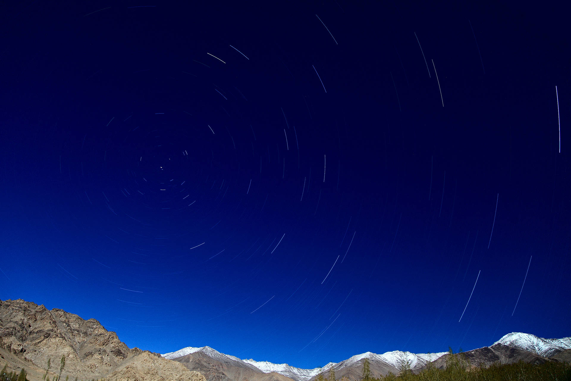 星軌在深藍色夜空下，在積雪的山峰上劃出弧線。