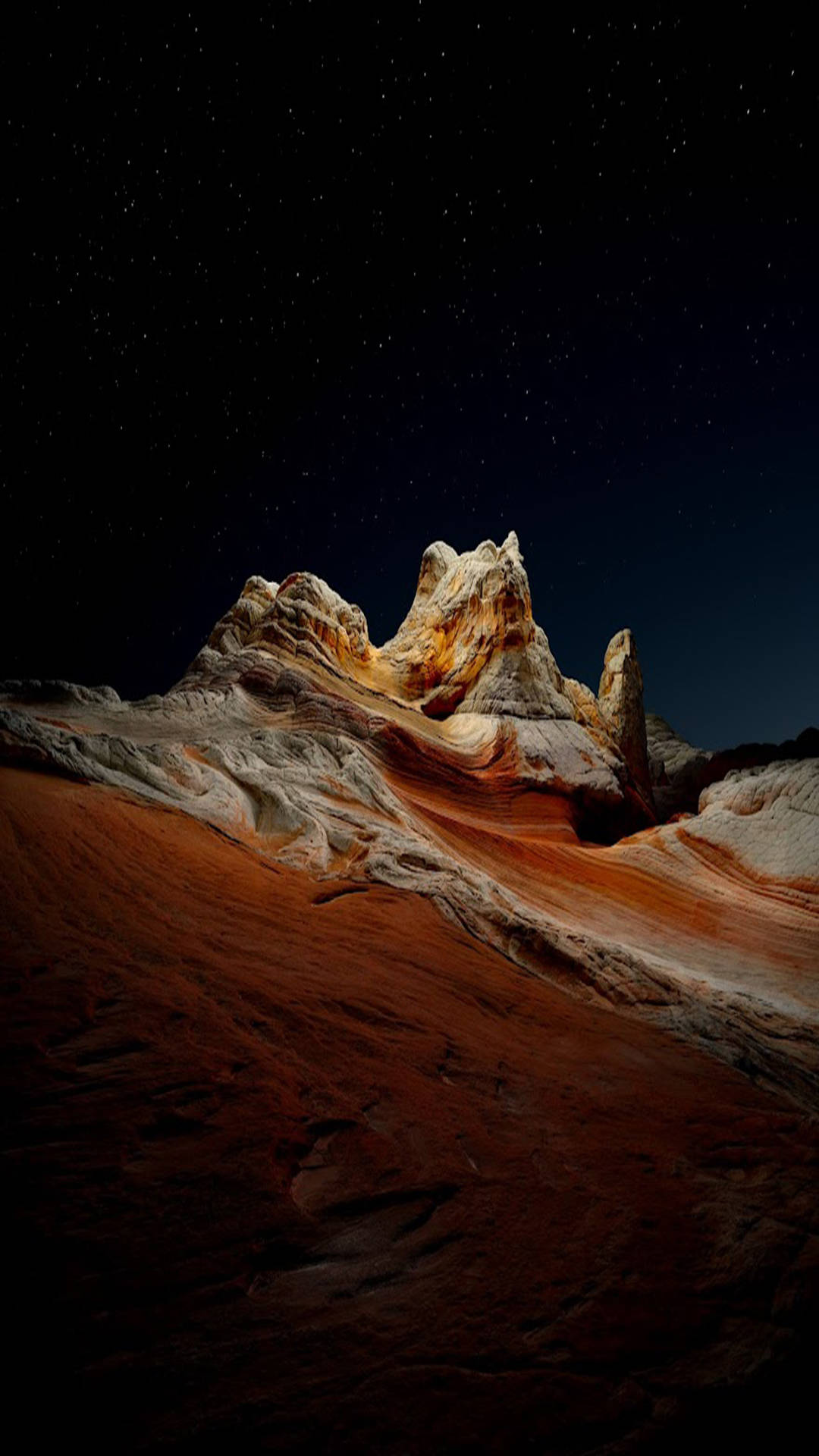 溫暖燈光下戲劇性沙漠岩層上的星空之夜。