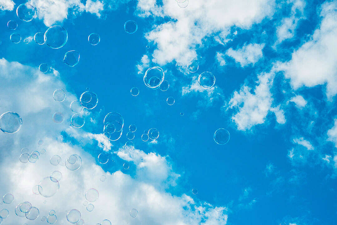 泡泡在明亮的藍天中飄動，伴隨著白雲。