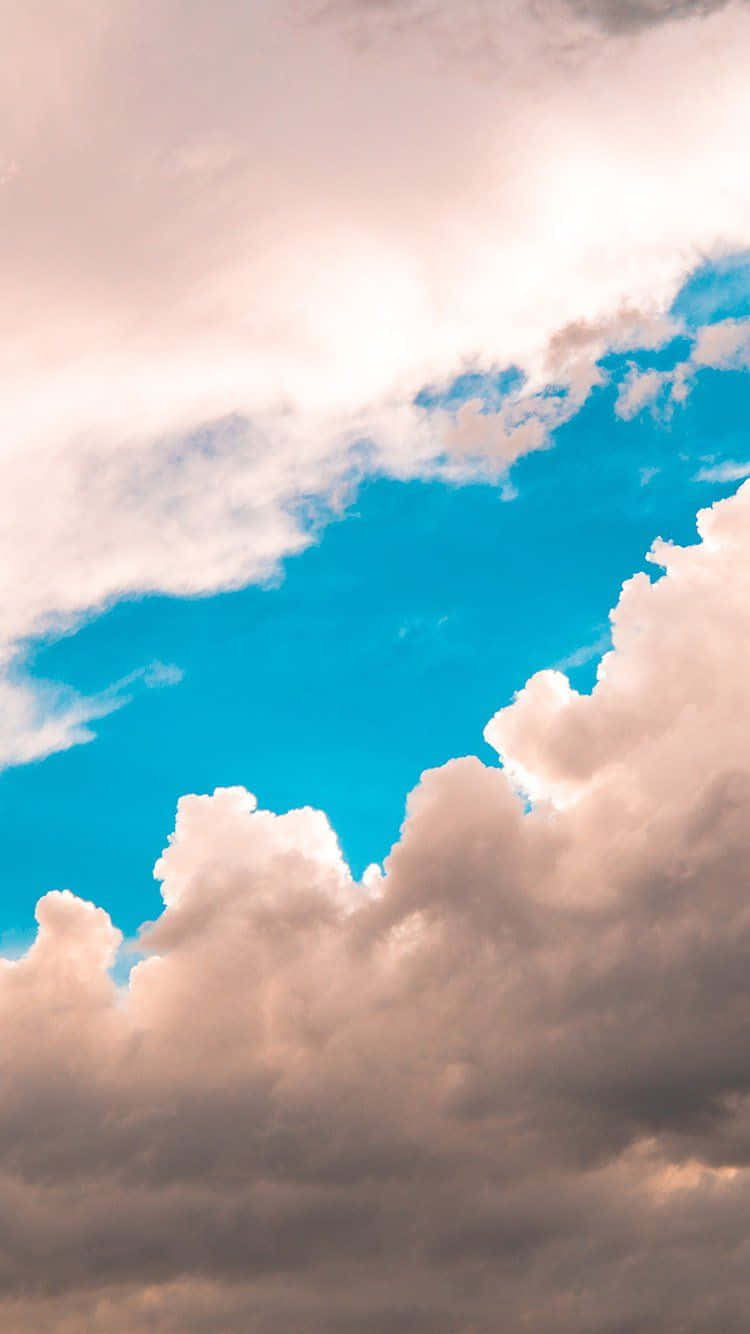藍天白雲的寧靜畫境 壁紙 — 廣闊的天空，蓬鬆的白雲沐浴在金色的陽光下，襯托著充滿活力的藍色背景。