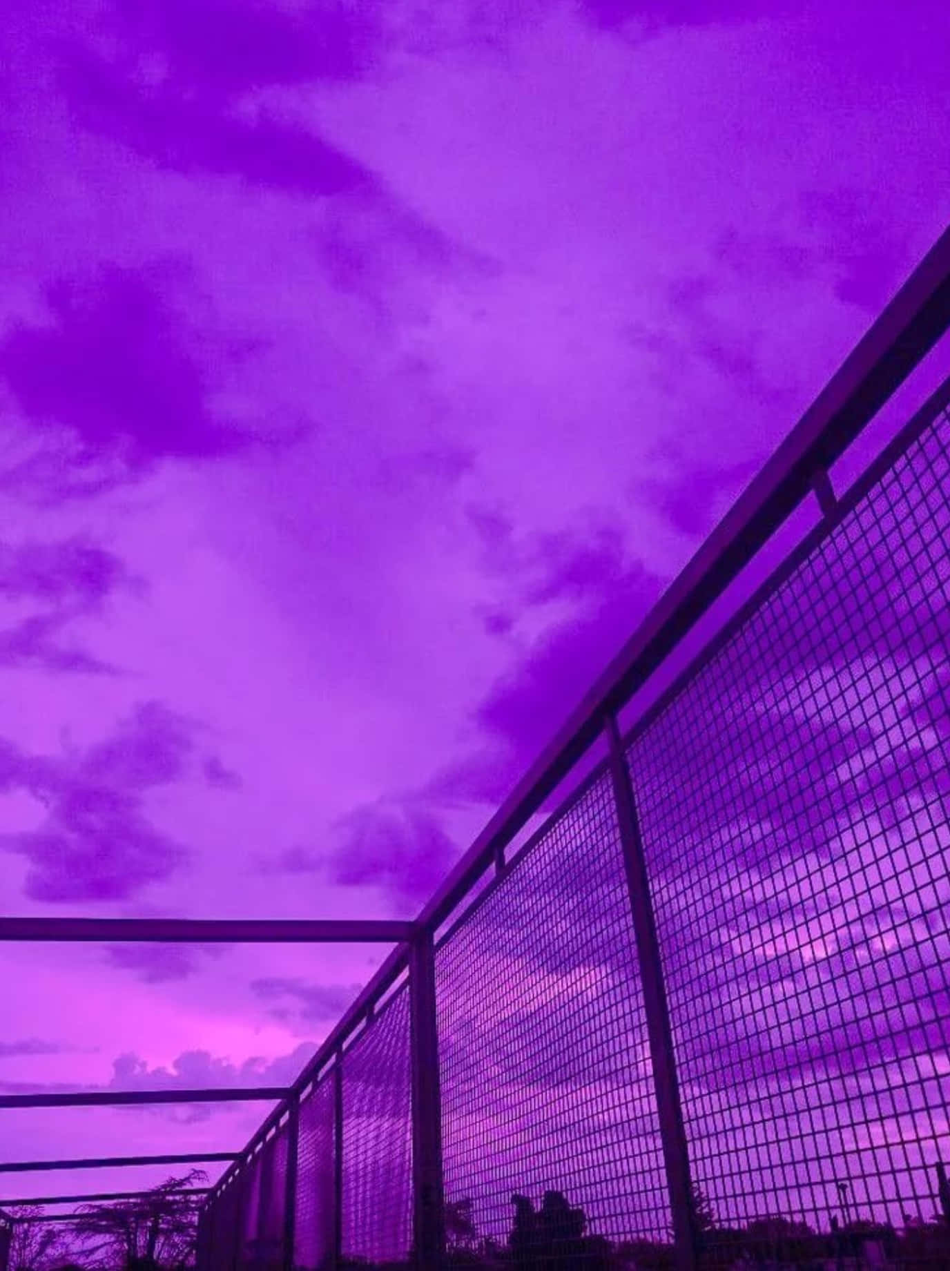 金屬圍欄後方的紫色暮色天空，帶有雲朵圖案。