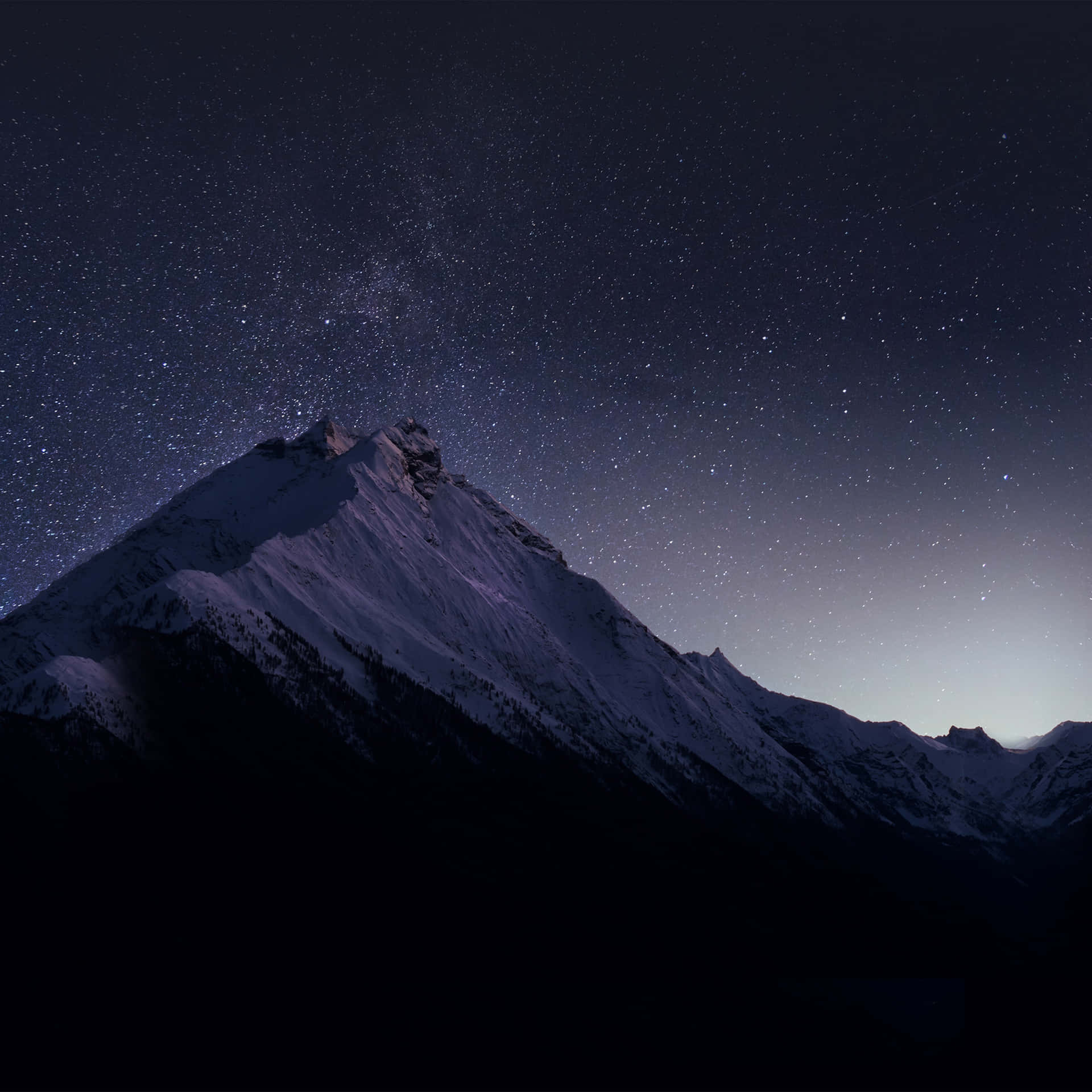 繁星點點的夜空下，白雪覆蓋的山峰，銀河可見。