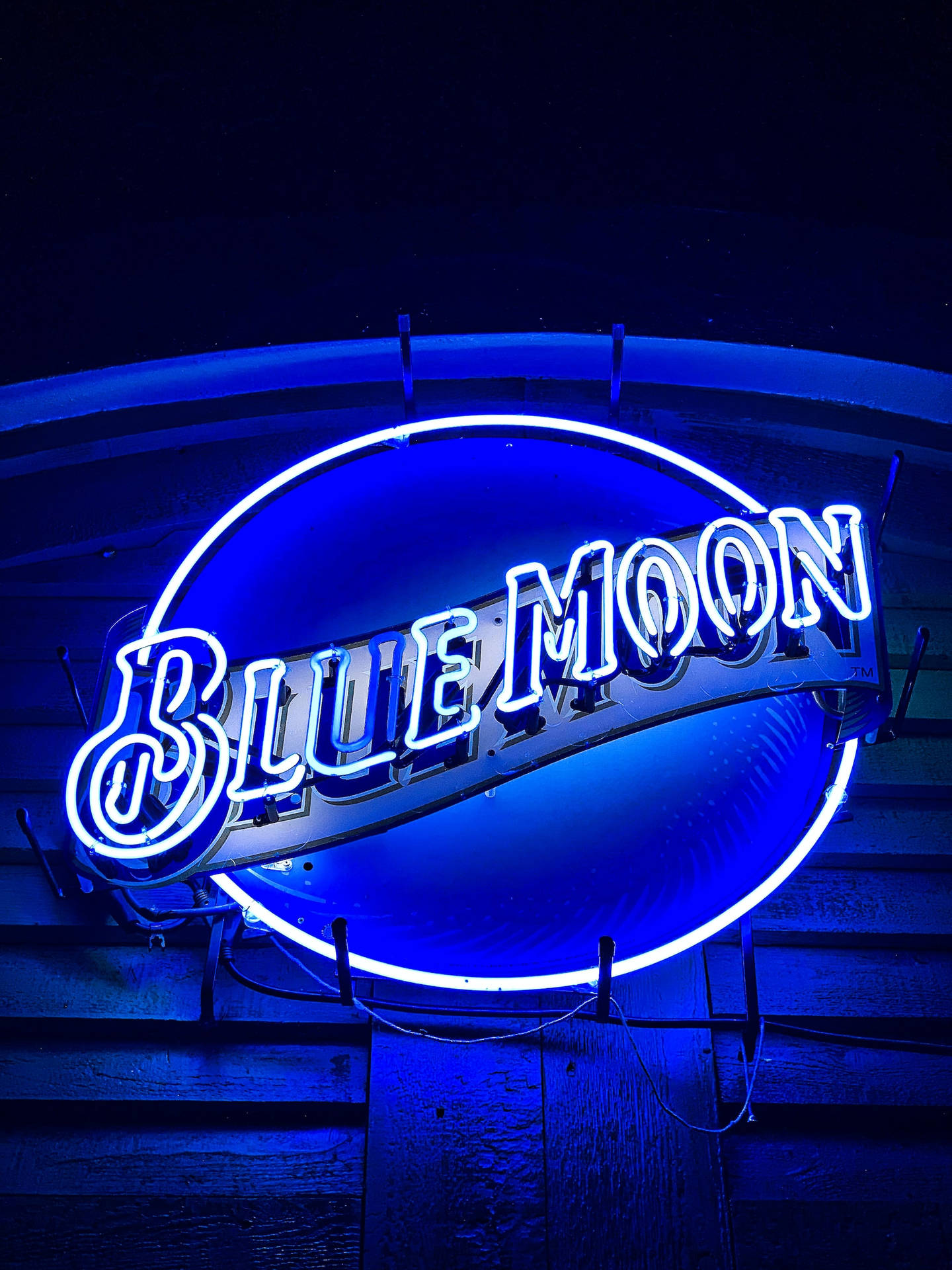 Blue Moon 霓虹燈牌在夜間於木牆上發出藍光。