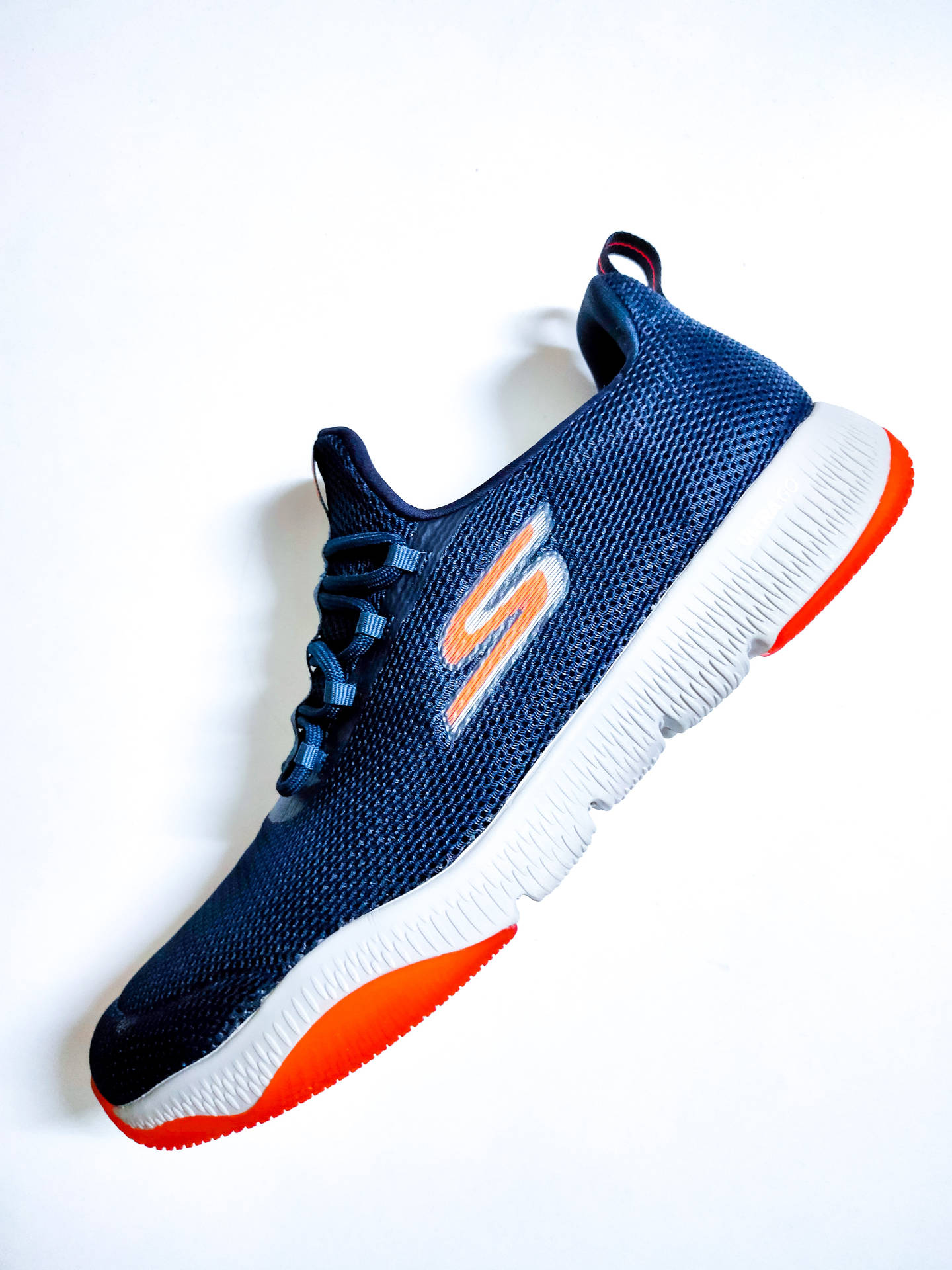 白色背景上帶有橙色細節的藍色Skechers運動鞋