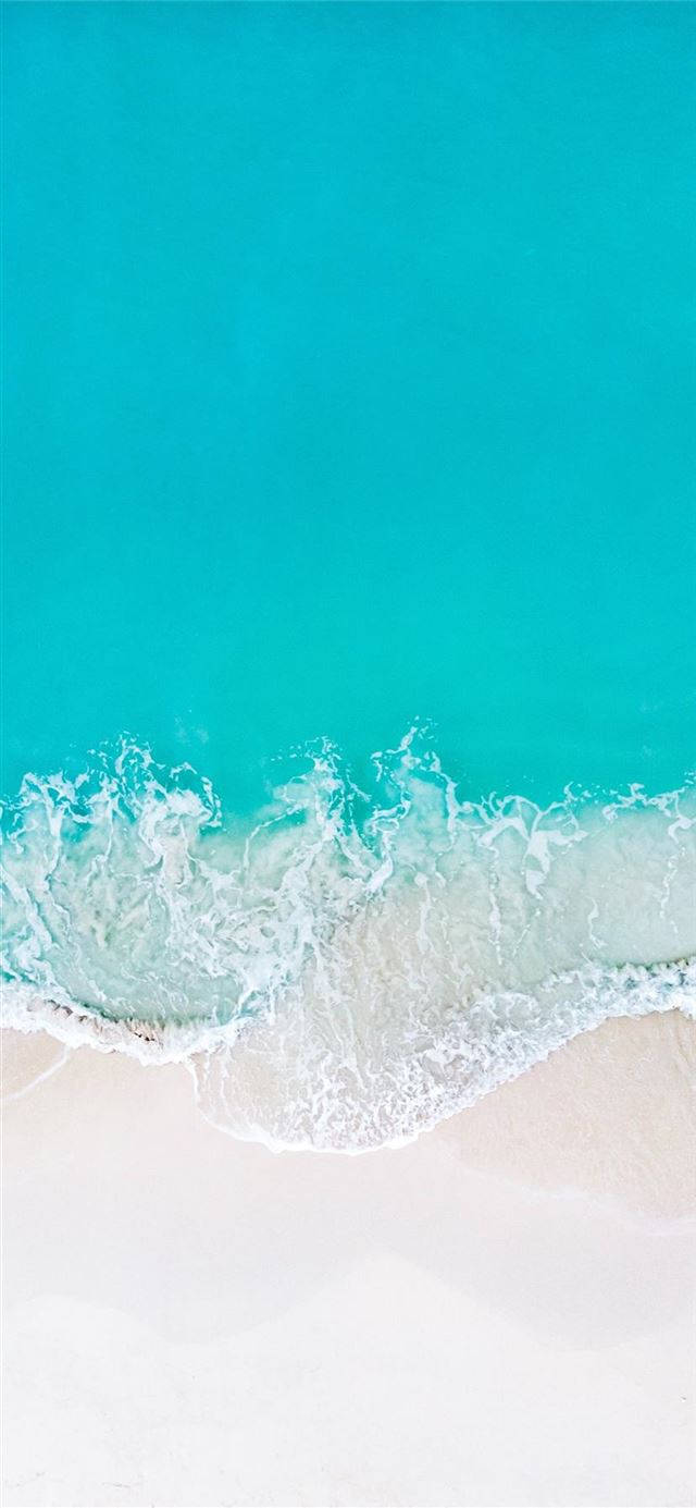 碧綠色的海浪從上方輕輕地滾向白色沙灘。