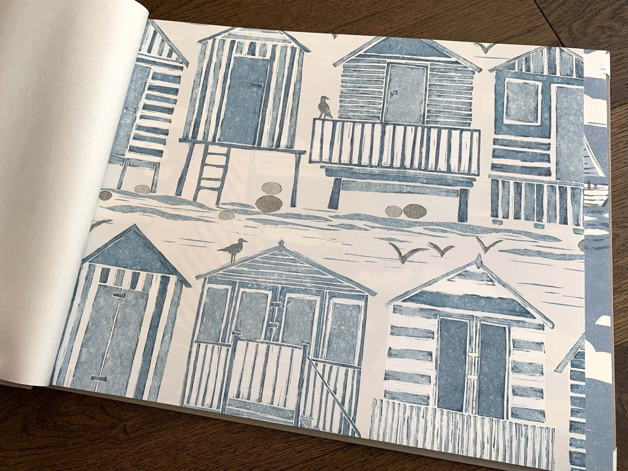 Beach Huts 桌布 壁紙 — 藍白插圖風格的海灘小屋牆紙圖案，小鳥在木質表面上空飛翔。