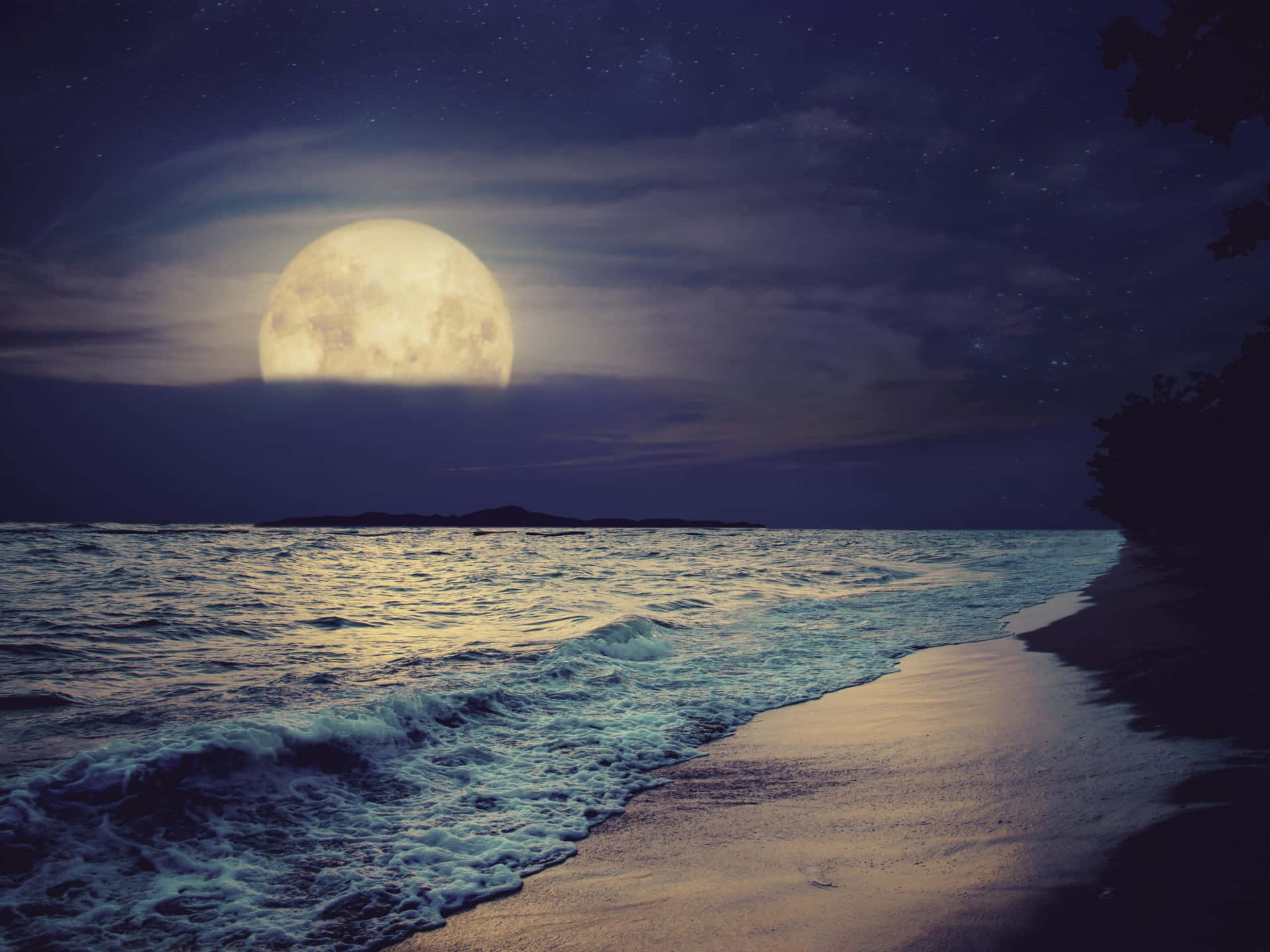 夜晚海洋上的滿月，沙灘上有波浪，星空下