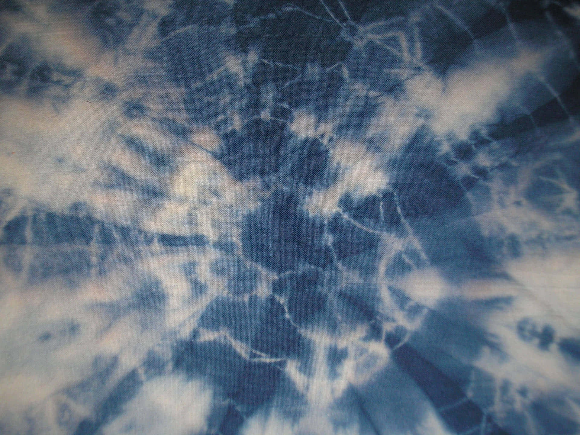 Blue Tie Dye 桌布 壁紙 — 藍白紮染布料的特寫，帶有漩渦圖案和可見的織物質地。