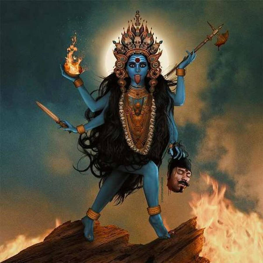 Goddess Kali 桌布 壁紙 — 藍皮膚多臂女神卡莉站在燃燒的木頭上，手持武器和一個被斬下的頭顱，背景是暴風雨的天空。
