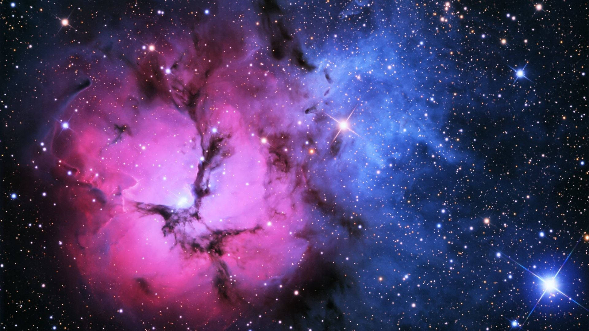 藍粉星系 壁紙 — 一個宇宙星雲在充滿明亮星星的星場中旋轉，呈現鮮豔的粉紅色和藍色。