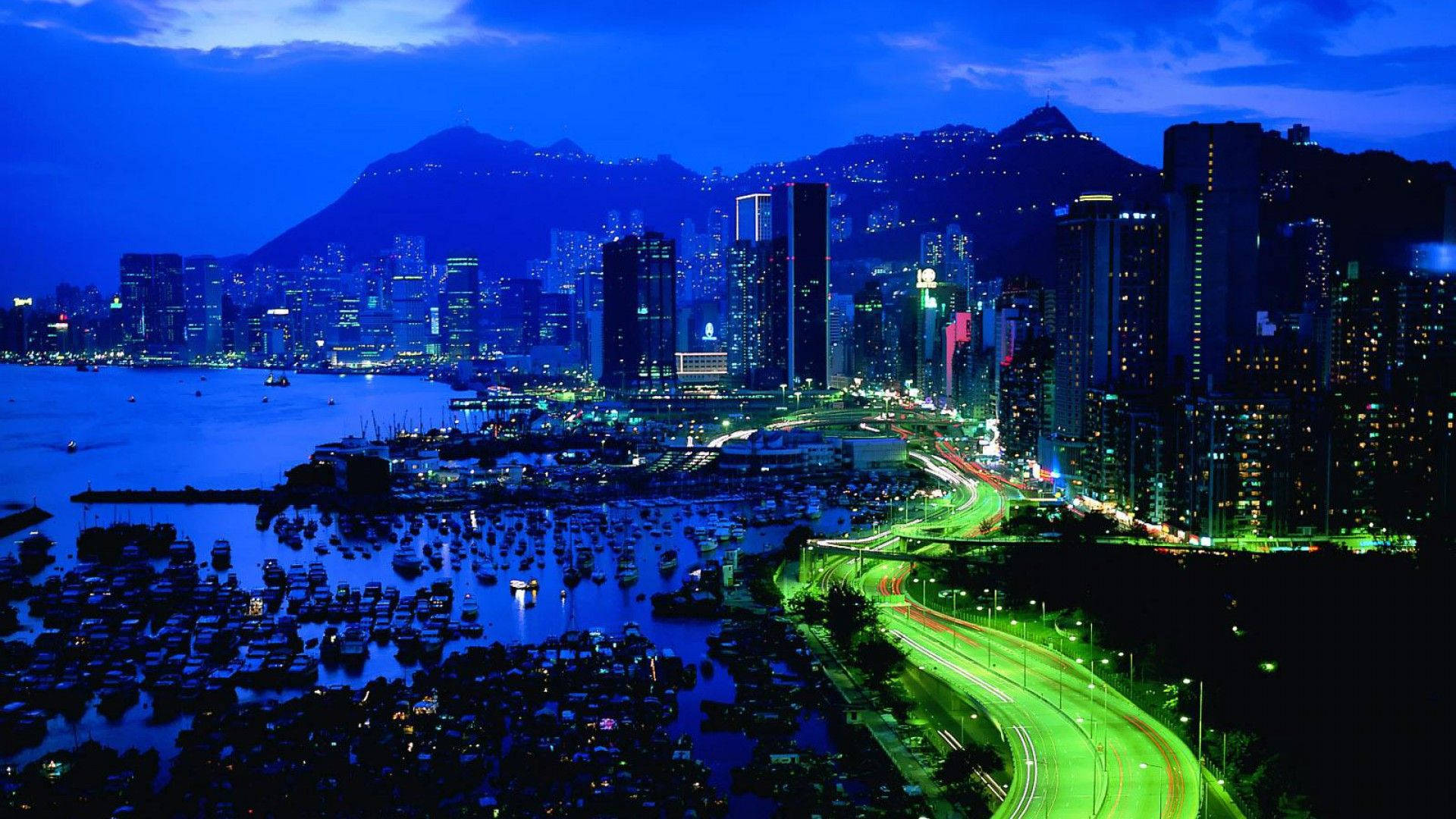 香港夜景，發光的建築物、船隻和霓虹高速公路。
