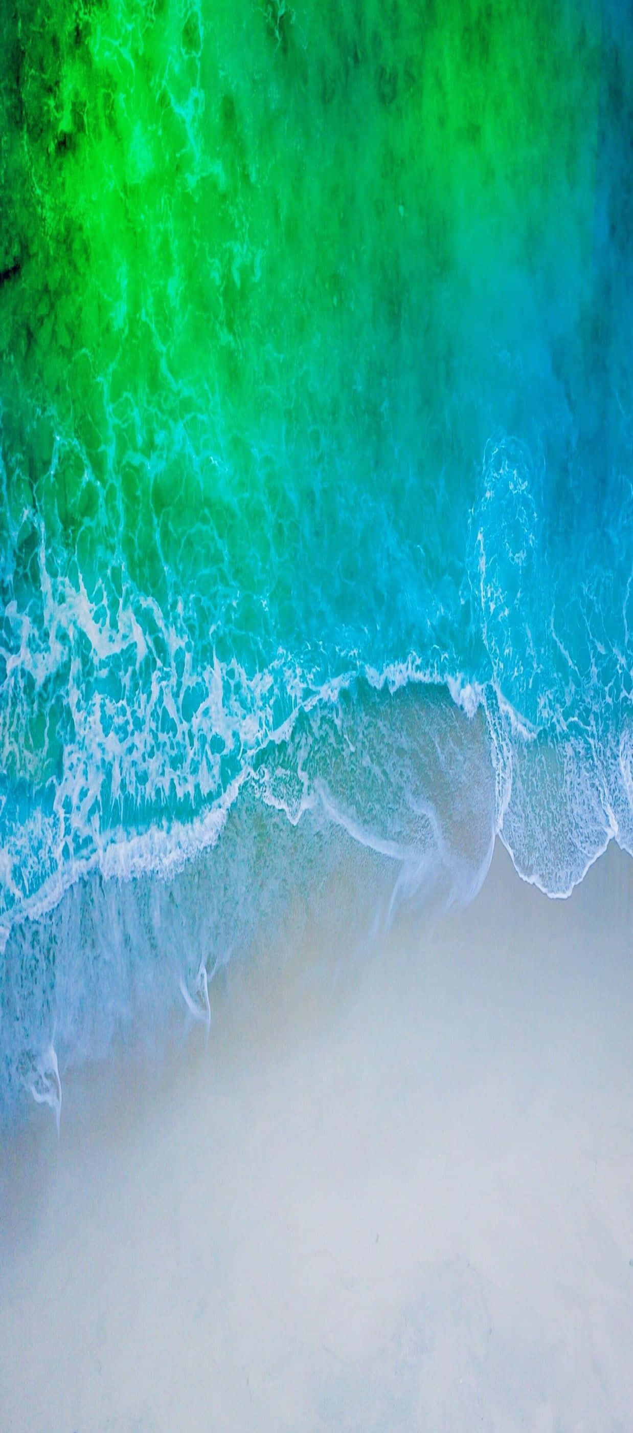 藍綠色海灘極簡iPhone圖片 壁紙 — 鮮豔的藍綠色和祖母綠海浪拍打著淡沙海岸，呈現出令人驚嘆的空中景觀。