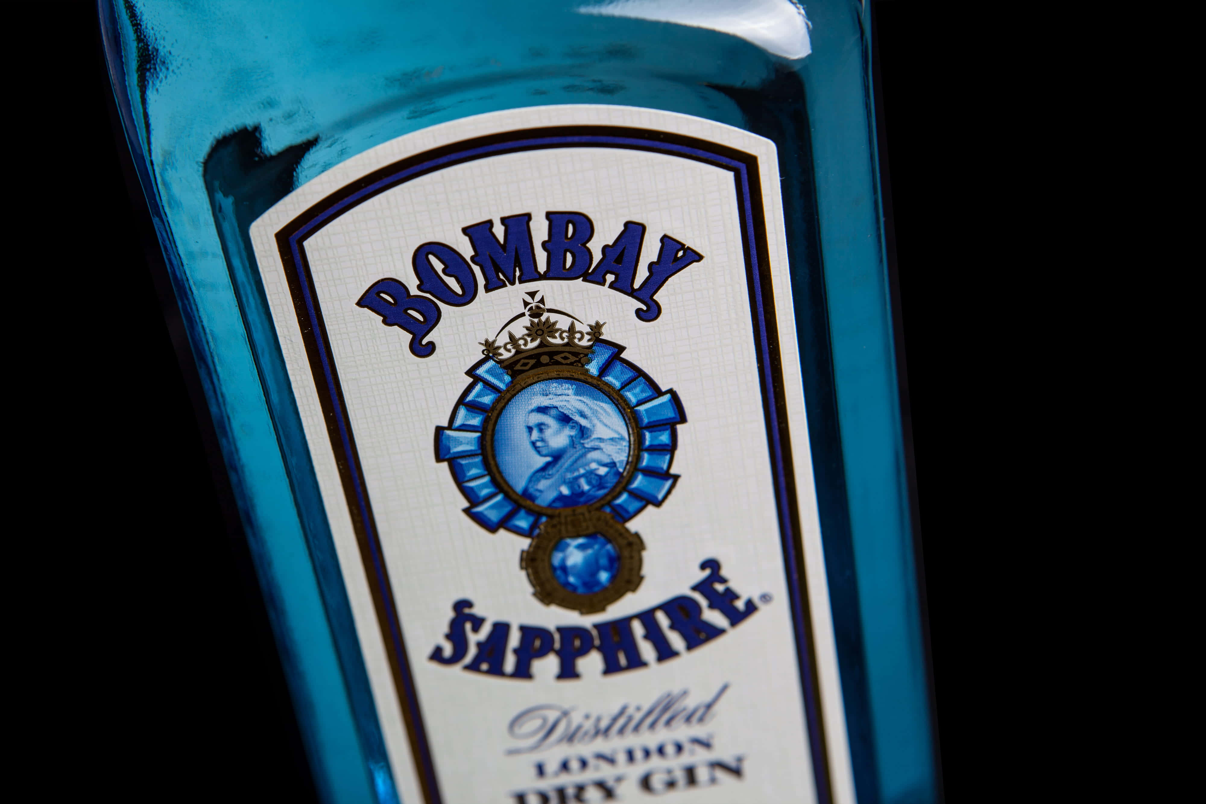 Sapphire Blue 桌布 壁紙 — 藍色Bombay Sapphire氈酒瓶標籤的特寫，背景為黑色。