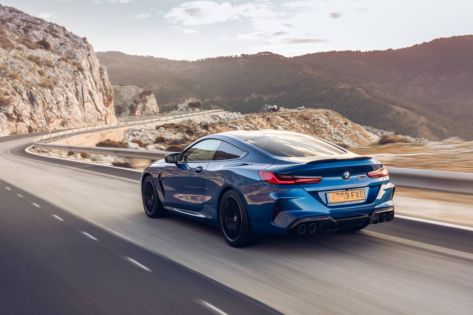藍色BMW M8 Coupe在日落時分的山路上疾馳