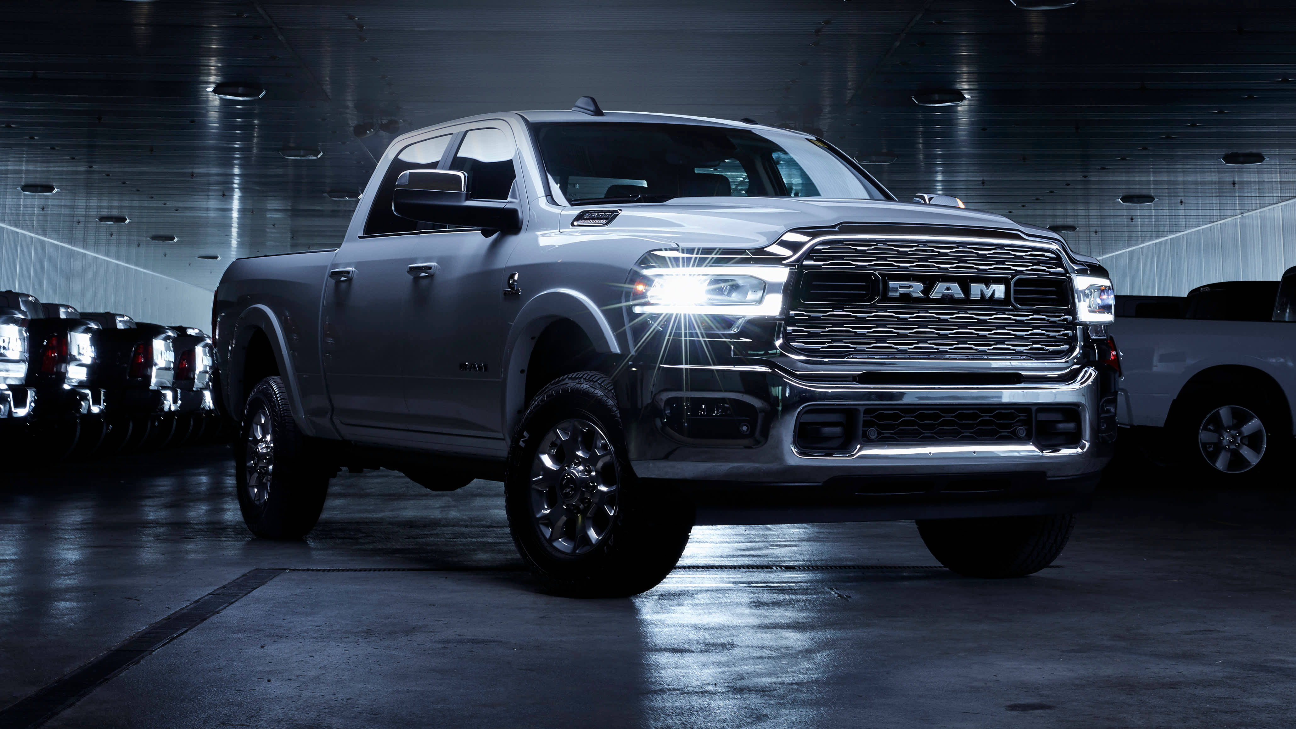 藍色RAM Truck 2500 Laramie 壁紙 — 一輛時尚的銀色Ram皮卡在黑暗的工業車庫中，在戲劇性的攝影棚燈光下閃閃發光。
