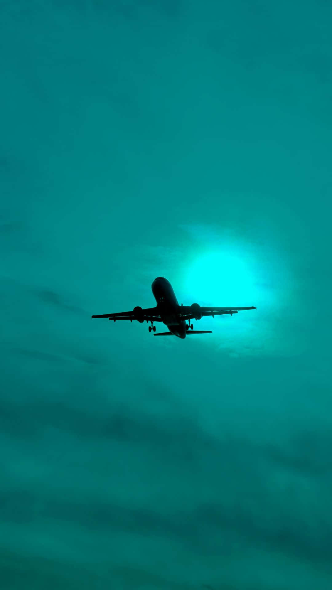 飛機剪影在發光的藍綠色天空中飛行