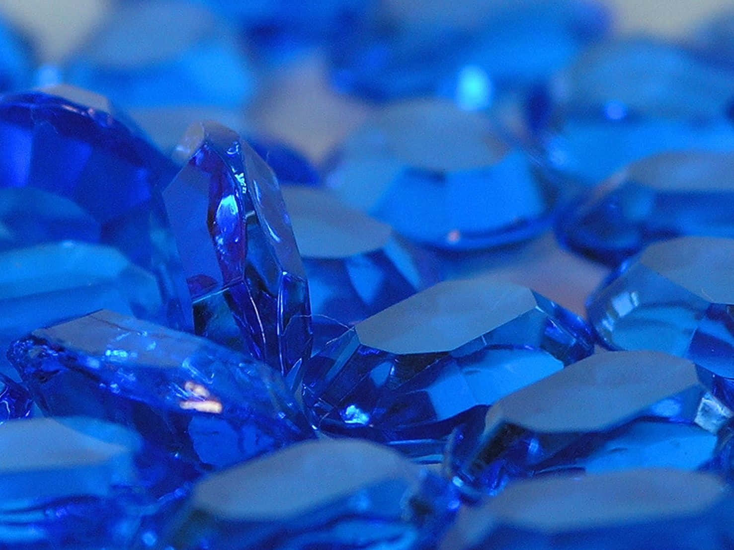 Sapphire Blue 桌布 壁紙 — 藍色刻面寶石在柔和光線下閃耀的特寫，帶有銳利反射和模糊背景。