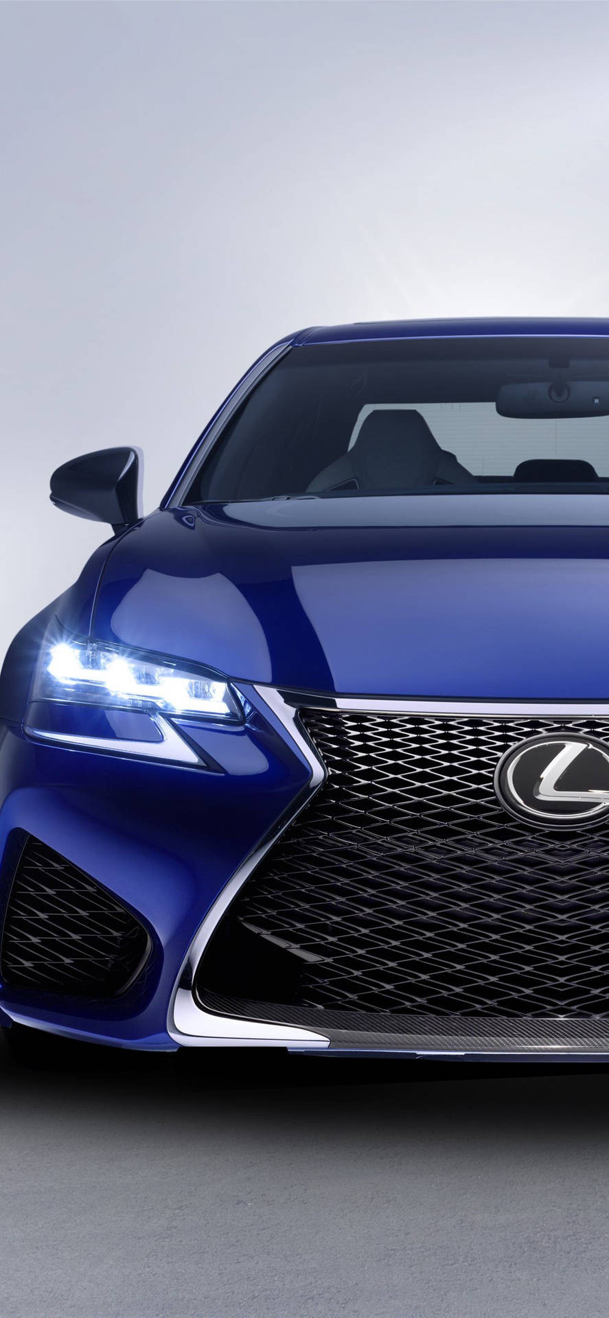 藍色Lexus車頭特寫，頭燈在工作室環境中亮起。