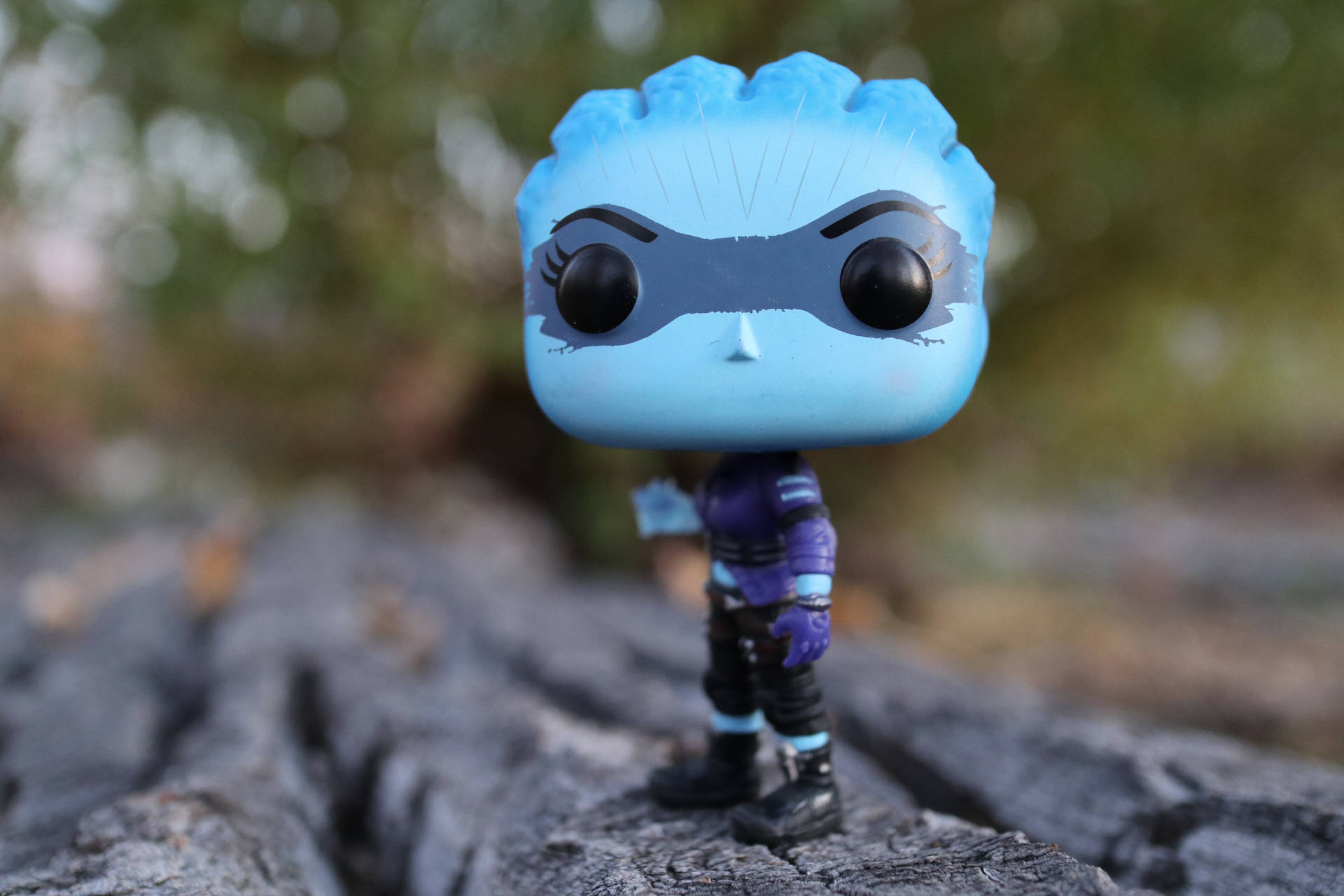 藍色Funko Pop公仔站在大自然的樹幹上。