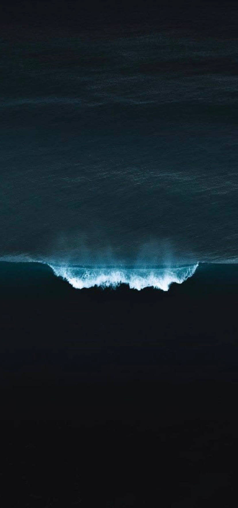 一個高聳的海浪在深色海水中破碎，帶有明亮的白色泡沫。