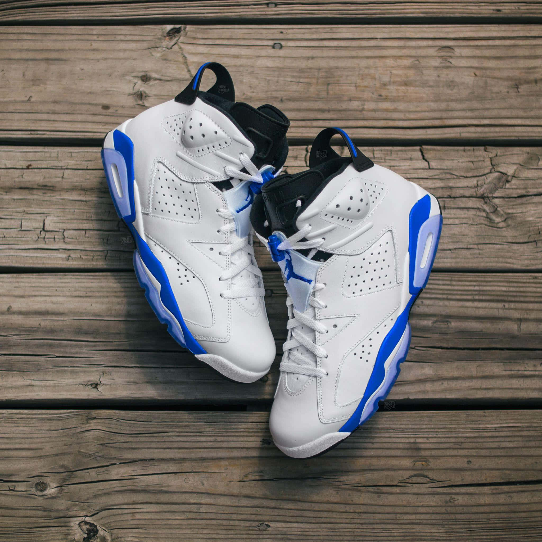 藍色喬丹 AJ 6 Sport Blue 色調 壁紙 — 一對白色和藍色的Jordan 6運動鞋放在風化的木板上，從上方俯視。