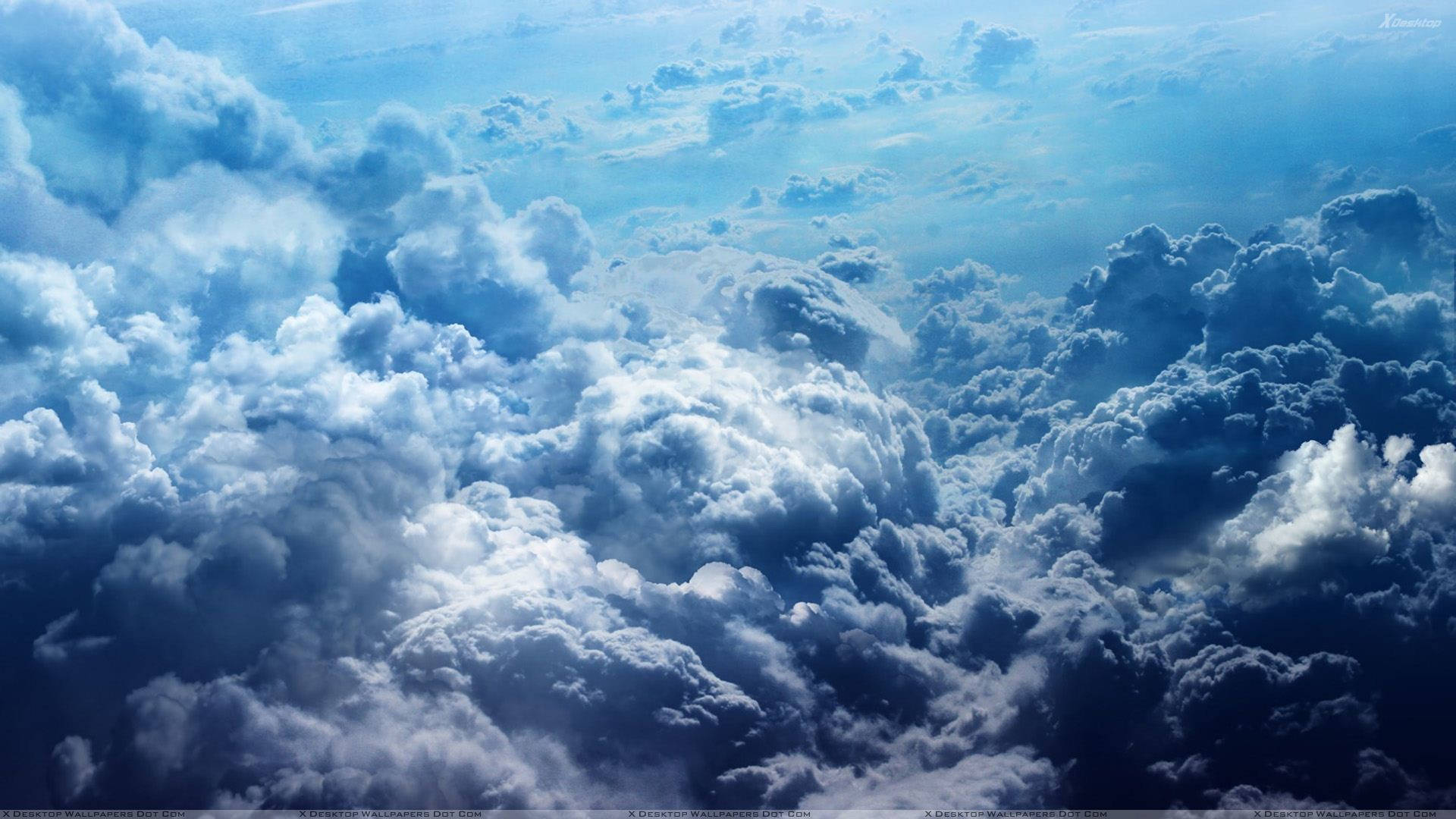 藍色多雲天空 壁紙 — 廣闊的蓬鬆雲朵在藍色和白色的色調中，在明亮的天空下無盡延伸。