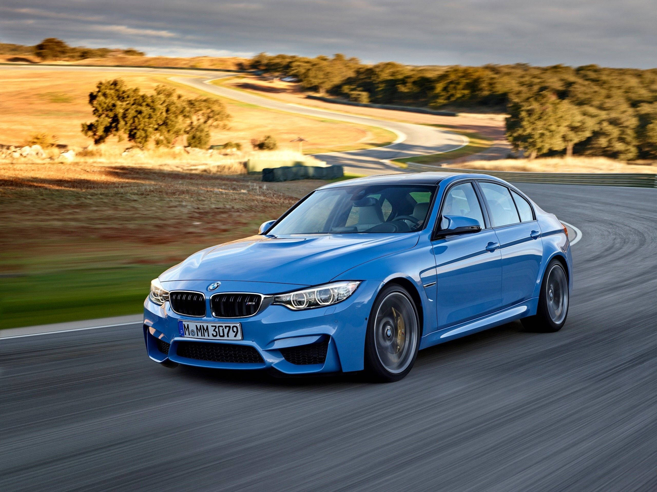 藍色寶馬駛過鄉間小路 壁紙 — 一輛充滿活力的藍色BMW M3轎車在陰天下行駛在蜿蜒的鄉村道路上。