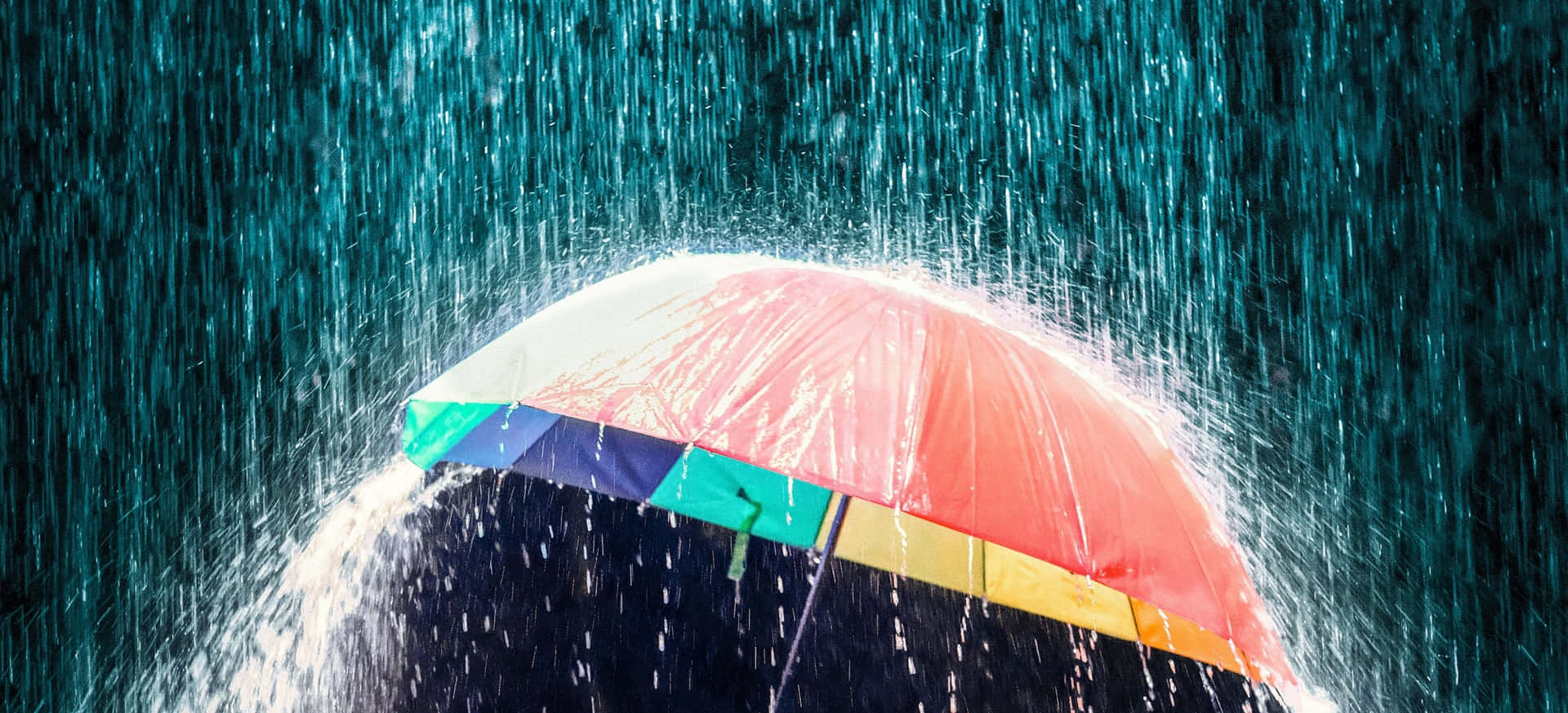 一把彩色雨傘在大雨中屹立不搖，周圍水花四濺。