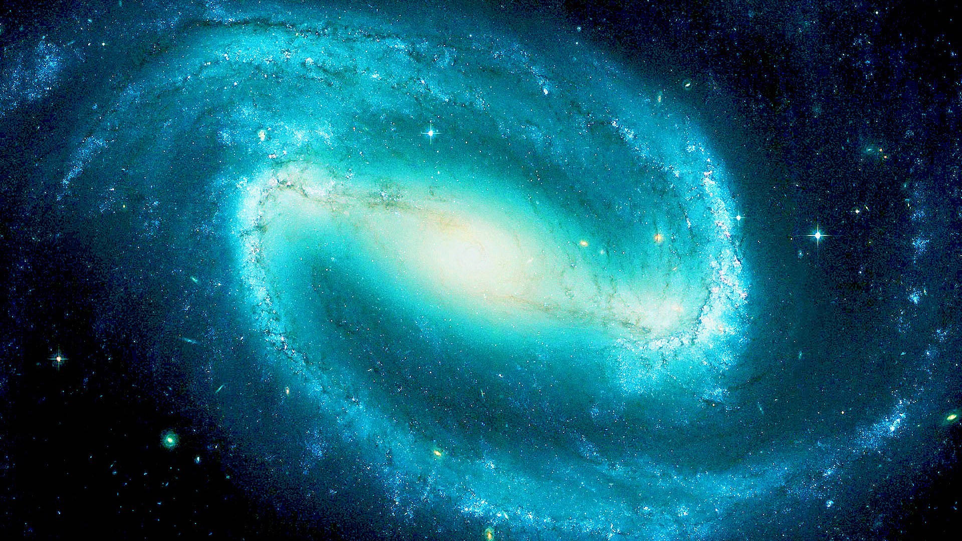 藍色星系中的天體 壁紙 — 一個令人驚嘆的螺旋星系，在繁星點點的宇宙虛空中閃耀著藍綠色和金色光芒。